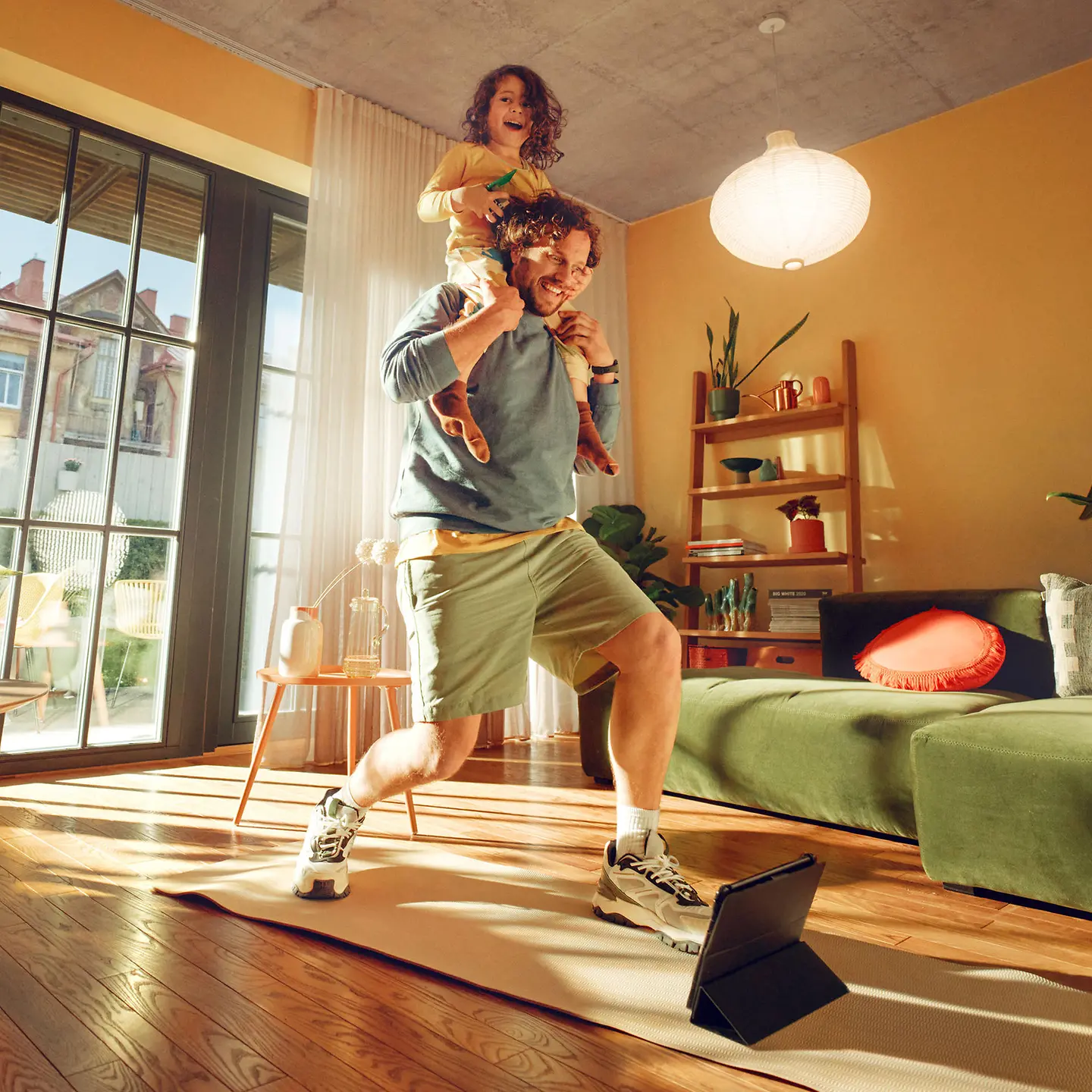 Ein Vater macht mit seiner Tochter auf dem Rücken Sportübungen. 