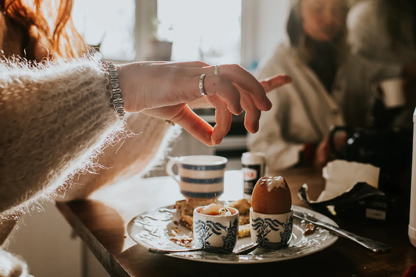Eine junge Frau streut etwas Salz auf ein gekochtes Ei