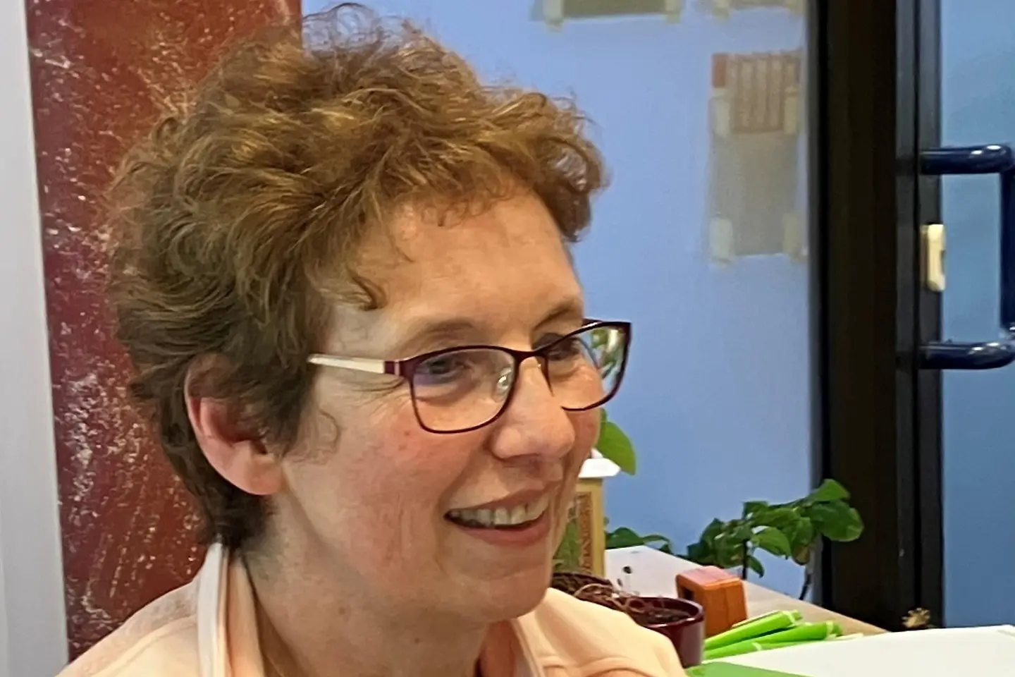 Eine Frau mit Brille und kurzen Haaren lächelt.