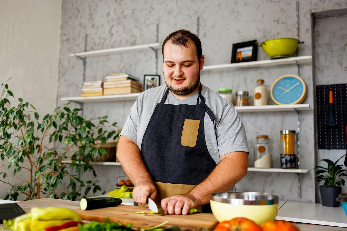 Ein übergewichtiger Mann steht in der Küche und schneidet Gemüse