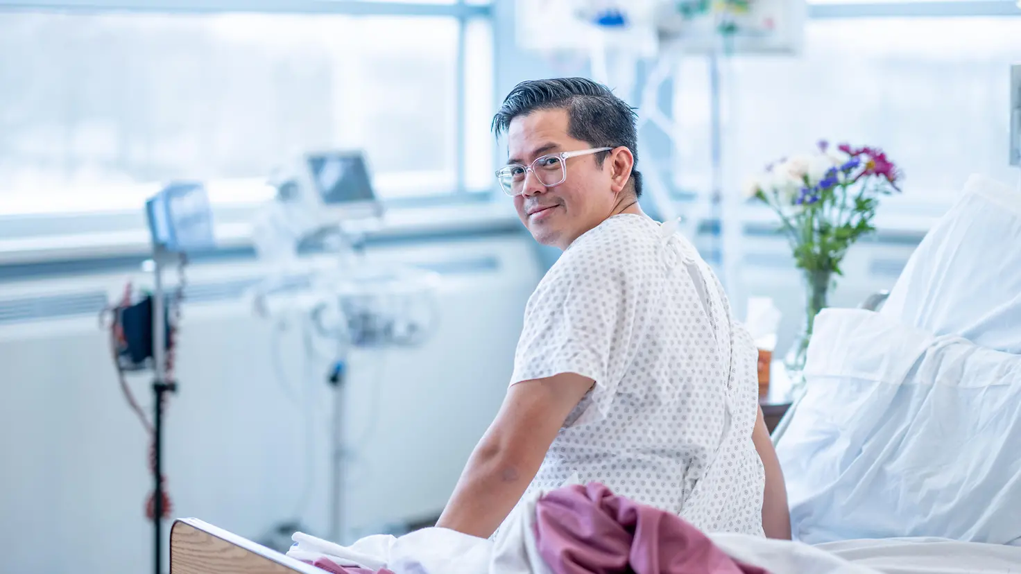 Männlicher Patient sitzt zufrieden in seinem Krankenhausbett