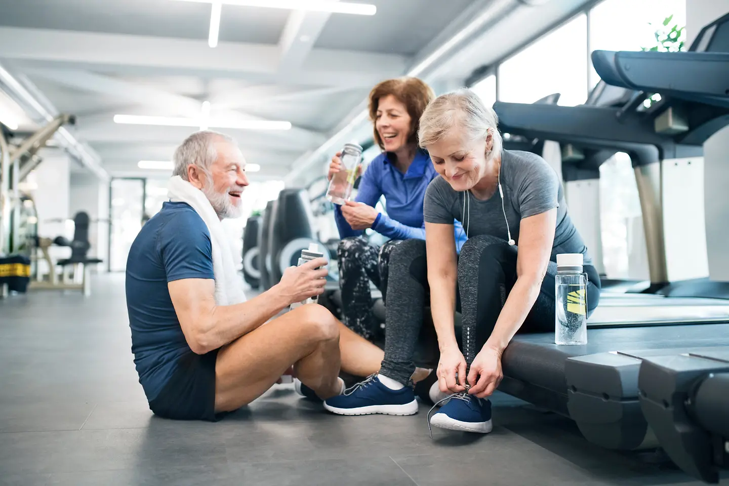 Gruppe fitter Seniorinnen und Senioren beim Ausruhen nach dem Training im Fitnessstudio