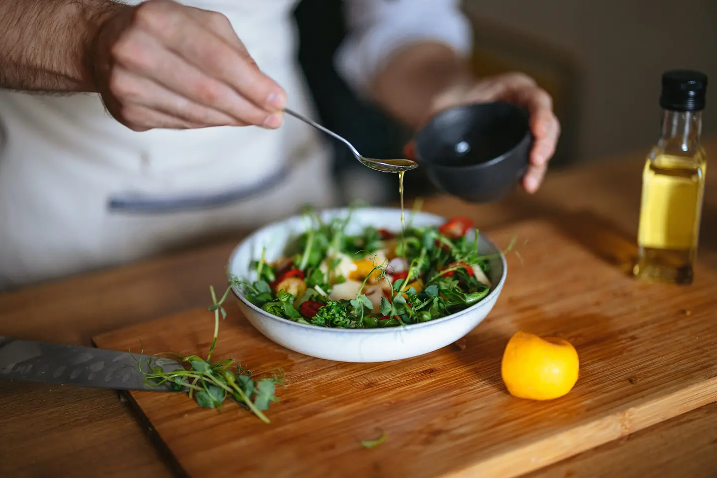 Eine Person verfeinert einen Salat mit Öl