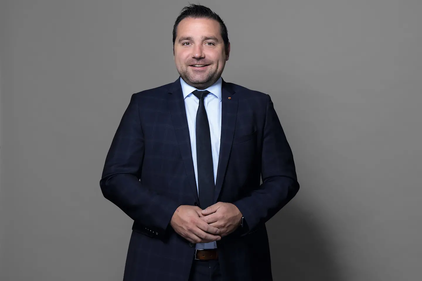 Bendikt Oster steht vor einer Wand.