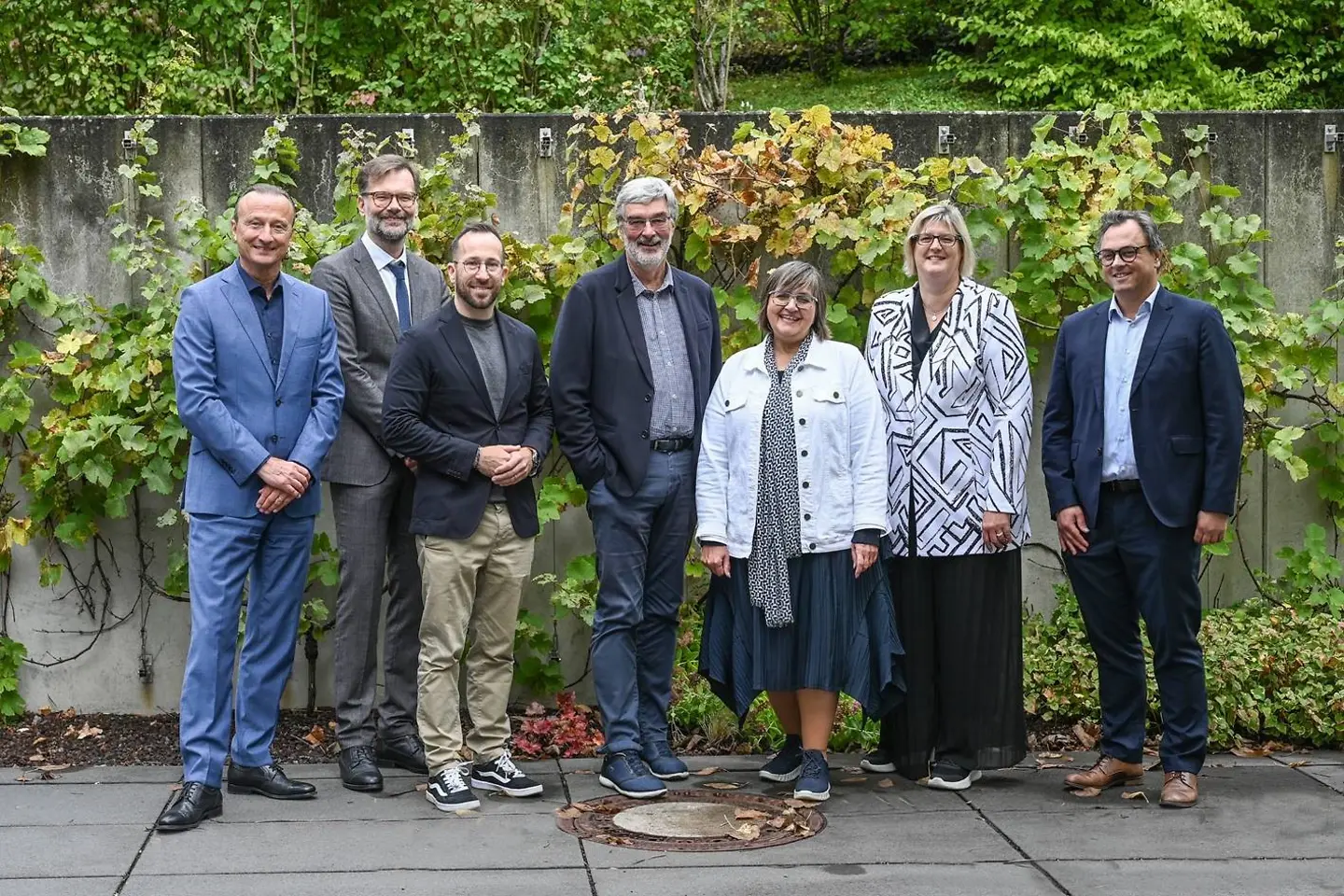 Diskutanten des Länderforums stehen vor einer bepflanzten Wand.