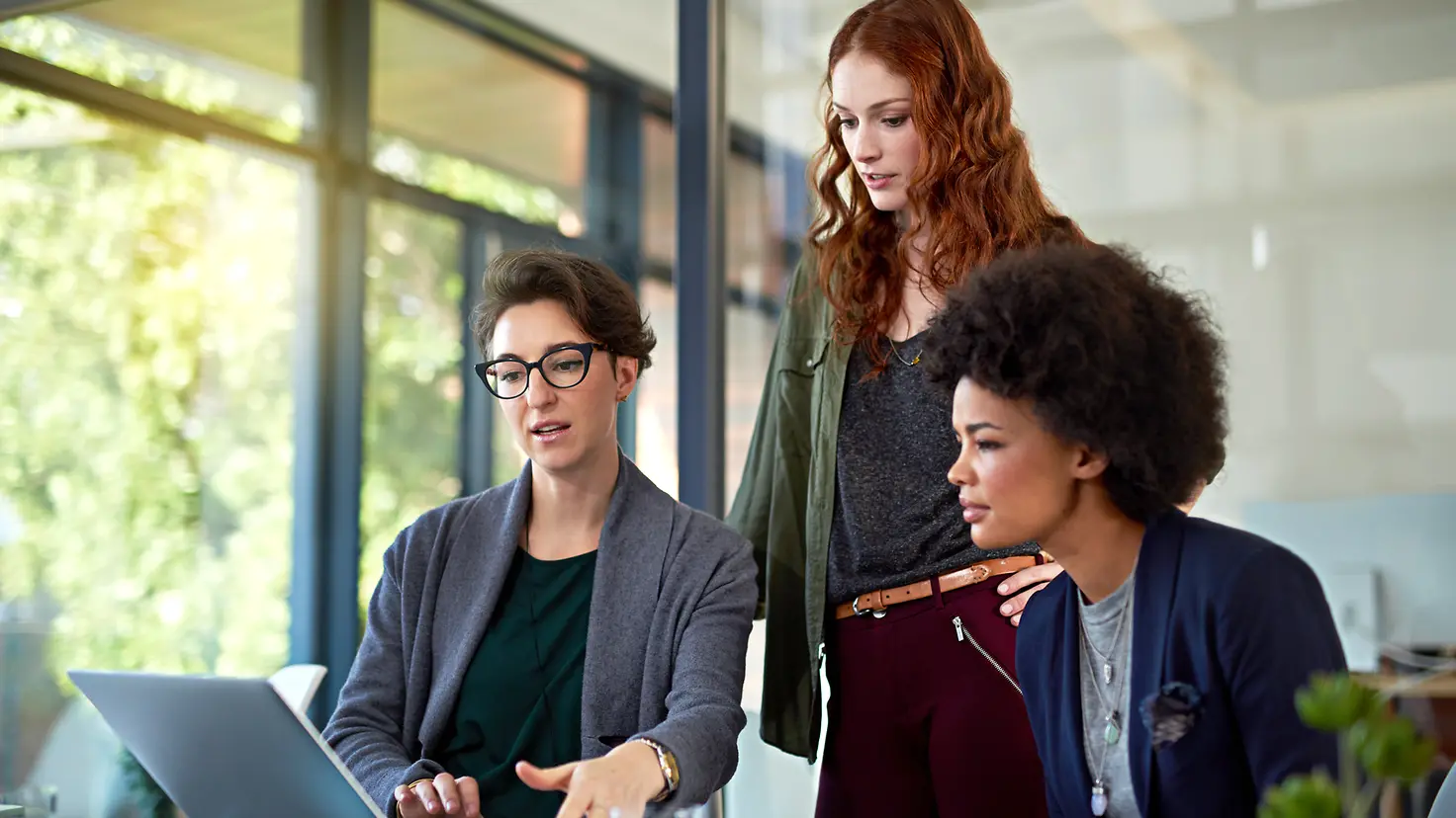 Drei Frauen schauen auf einen Monitor