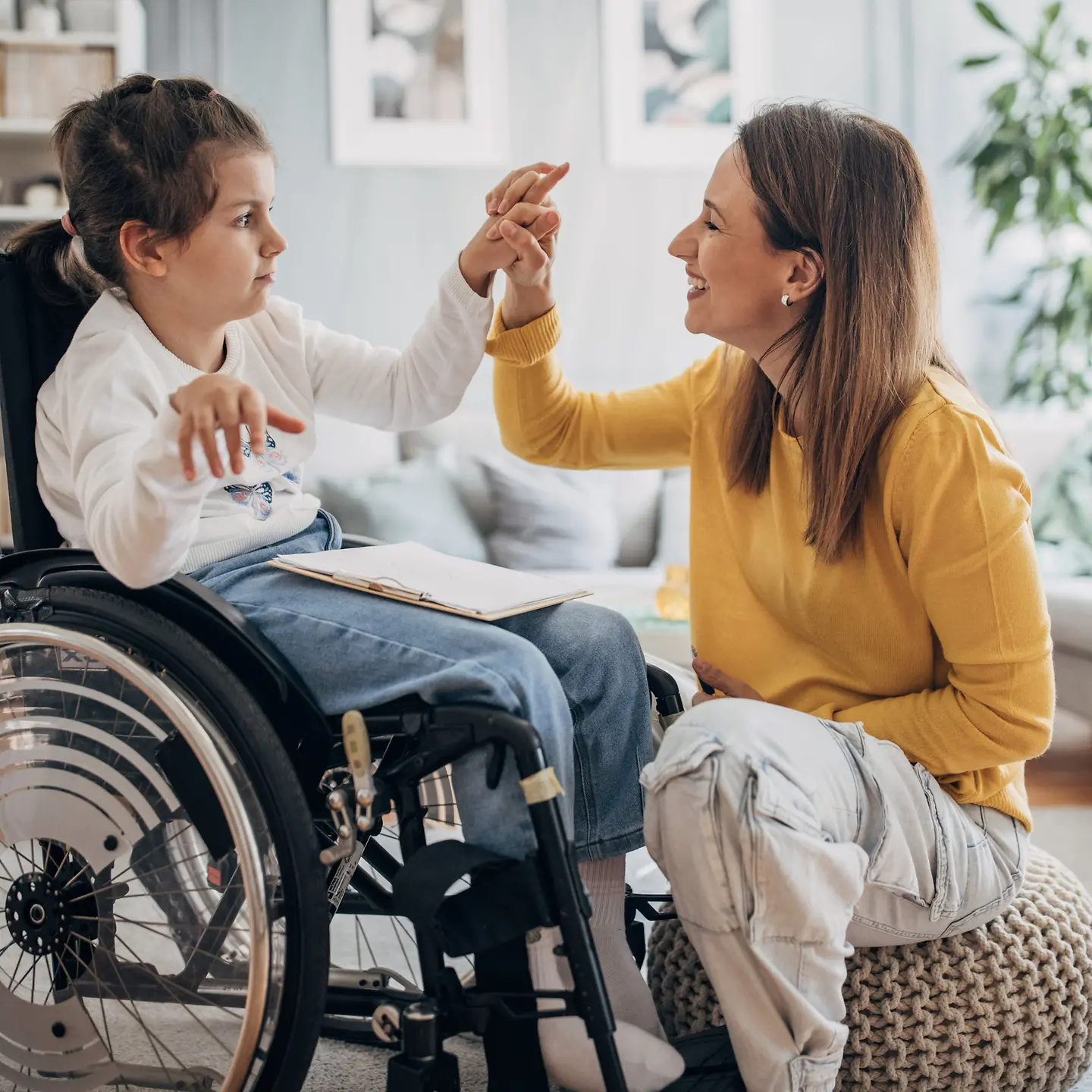 Ein Kind im Rollstuhl spielt mit seiner Mutter