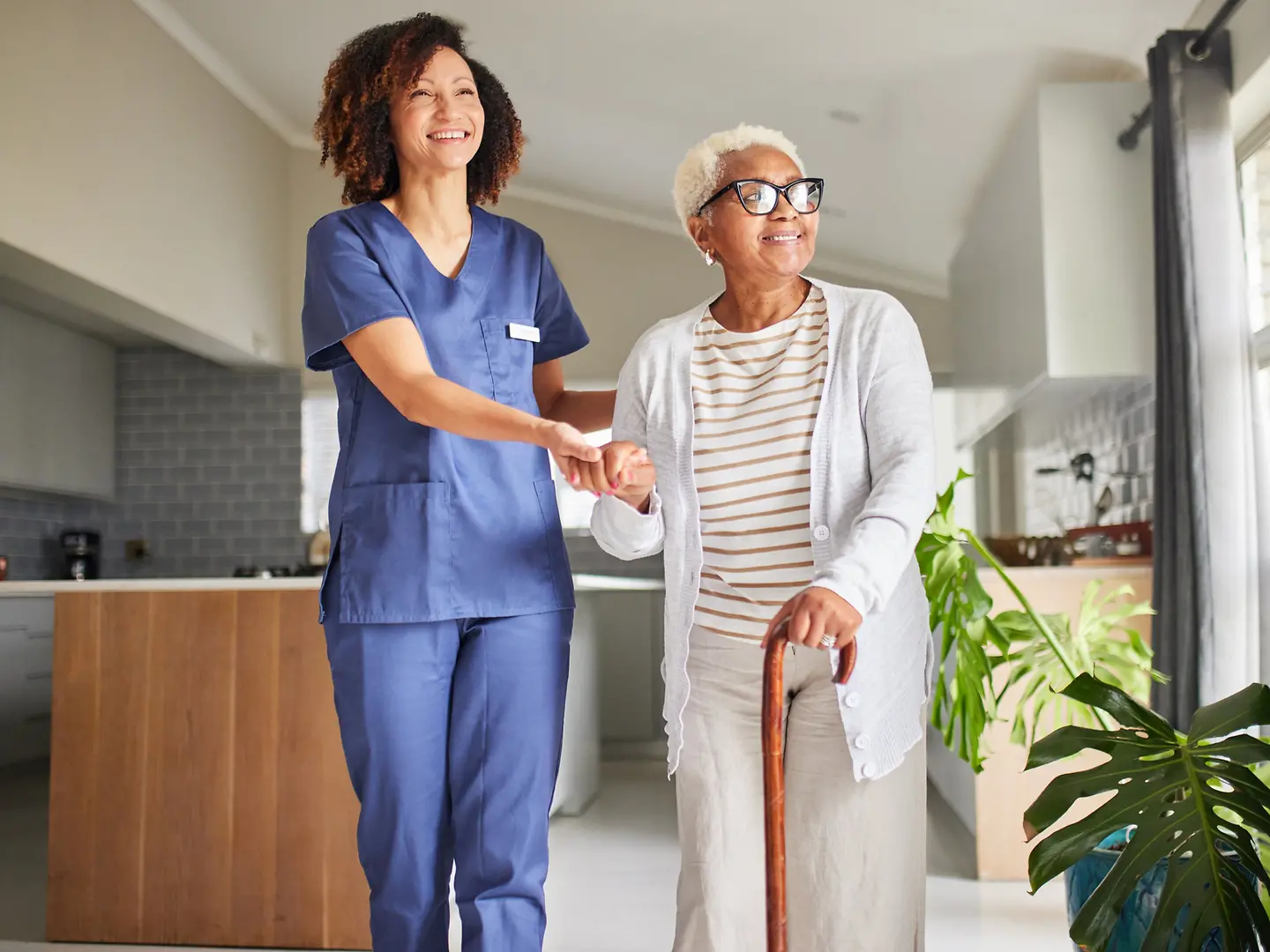 Eine Pflegerin kümmert sich um eine ältere Frau mit Gehstock