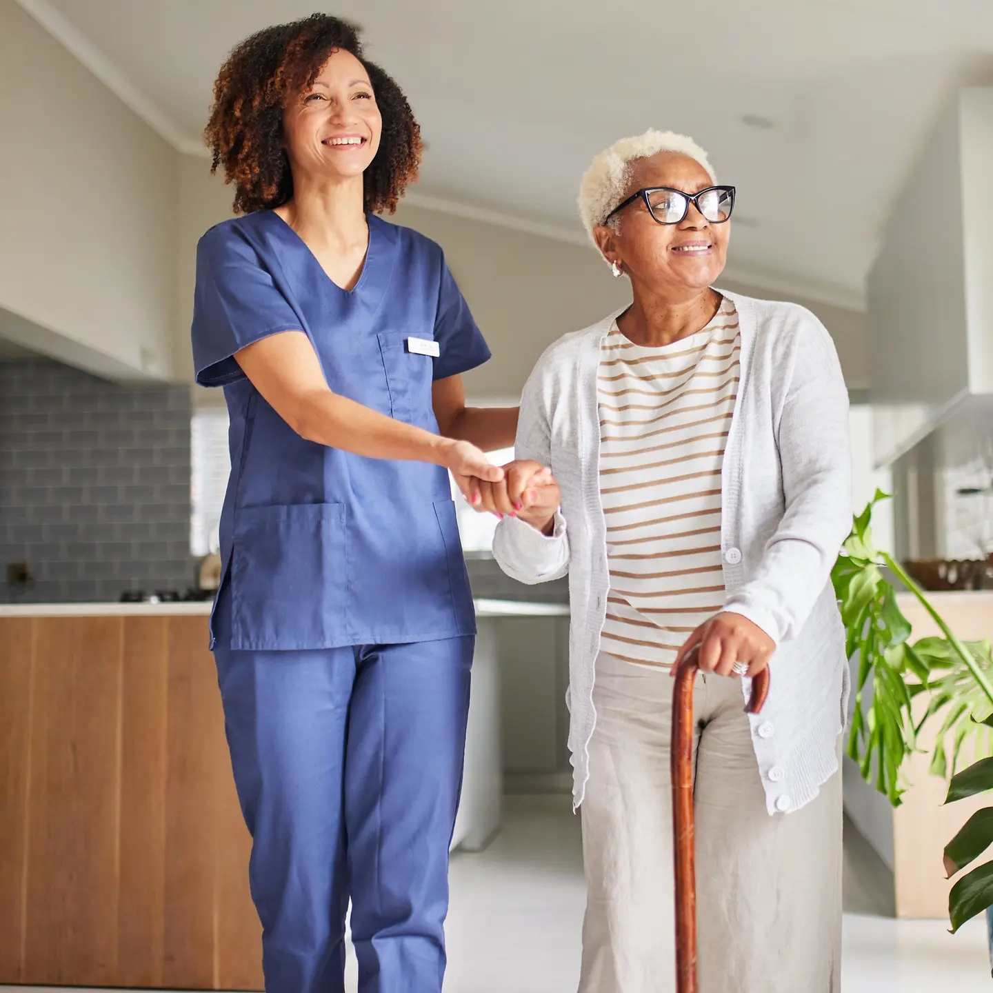 Eine Pflegerin kümmert sich um eine ältere Frau mit Gehstock
