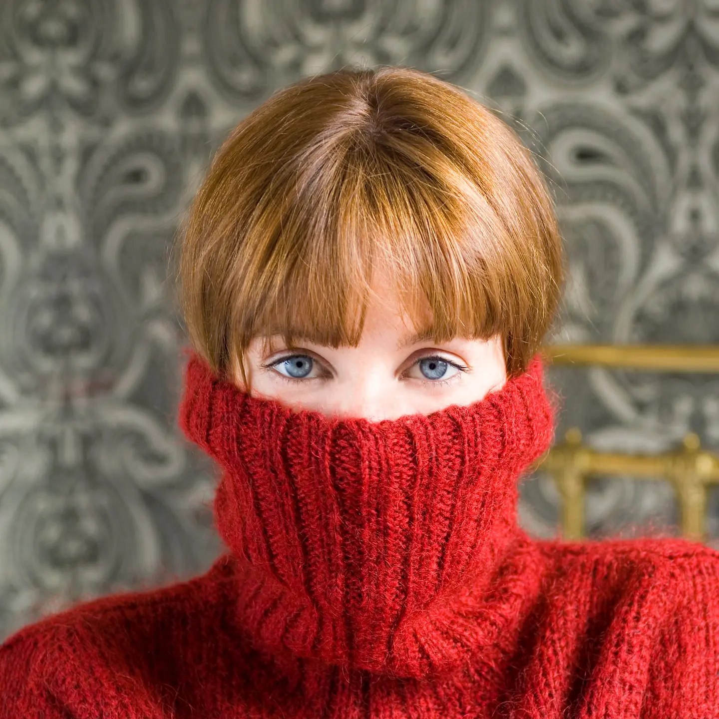 Junge Frau, die sich einen roten Pullover über ihr Gesicht zieht