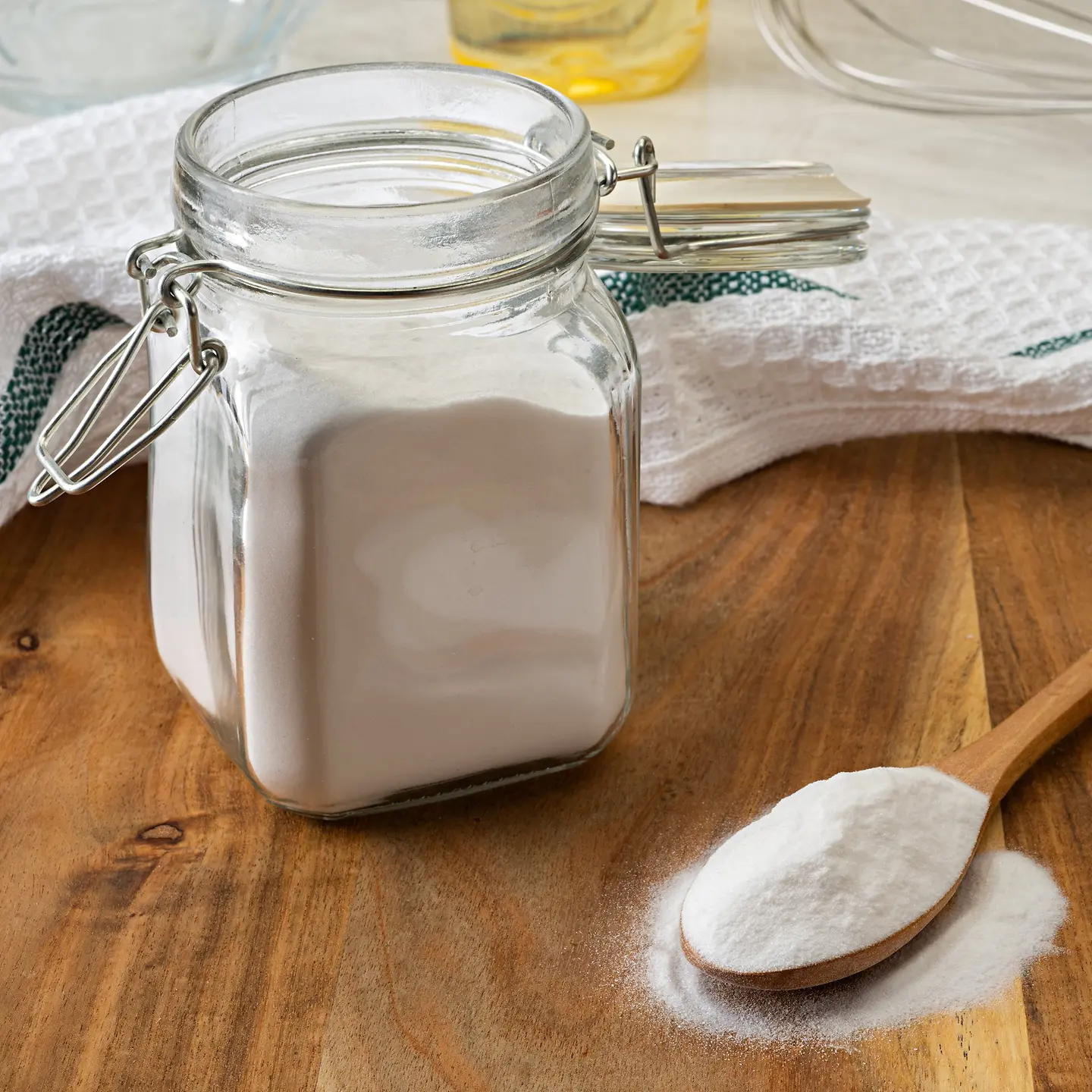Ein großes Glas und ein Löffel mit Backpulver auf einem Holztisch