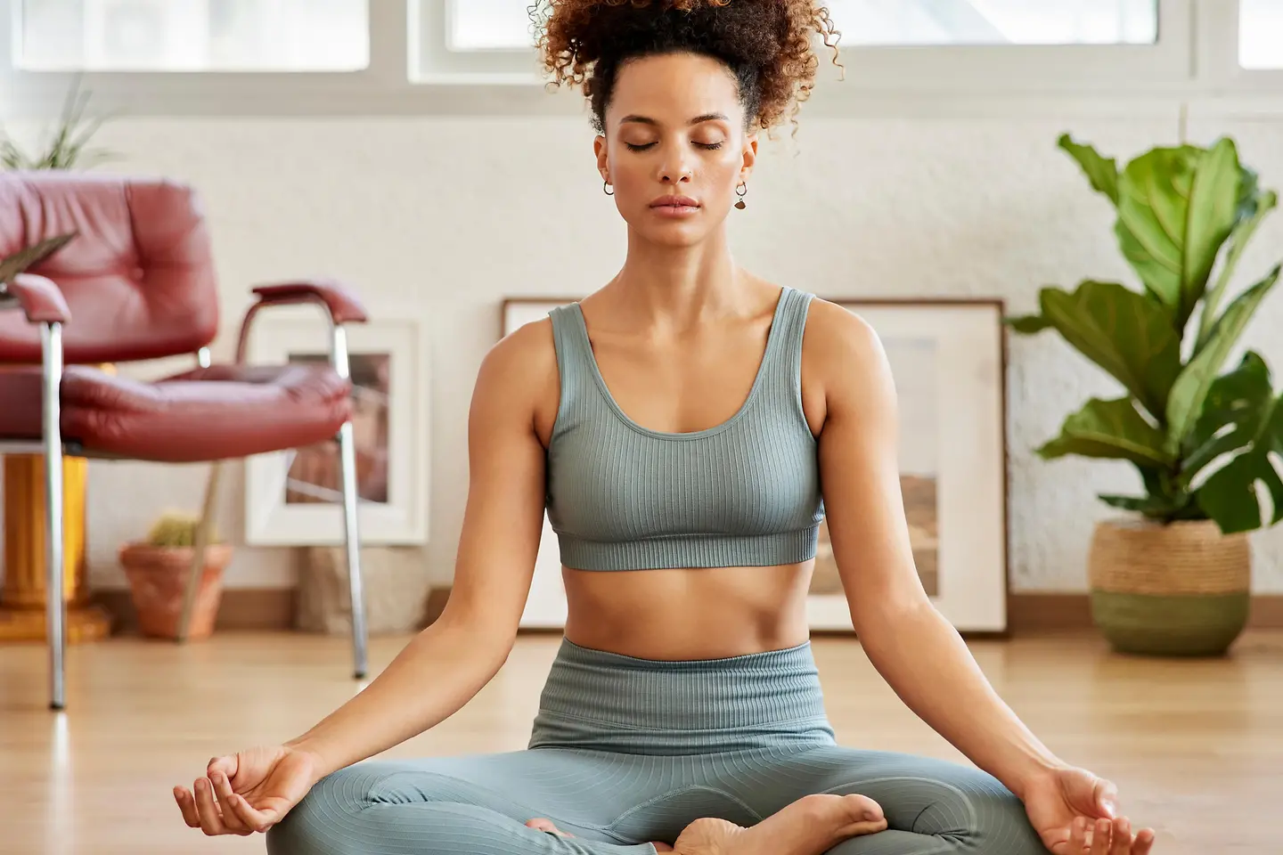 Eine junge Frau sitzt auf einer Yogamatte und macht Atemübungen