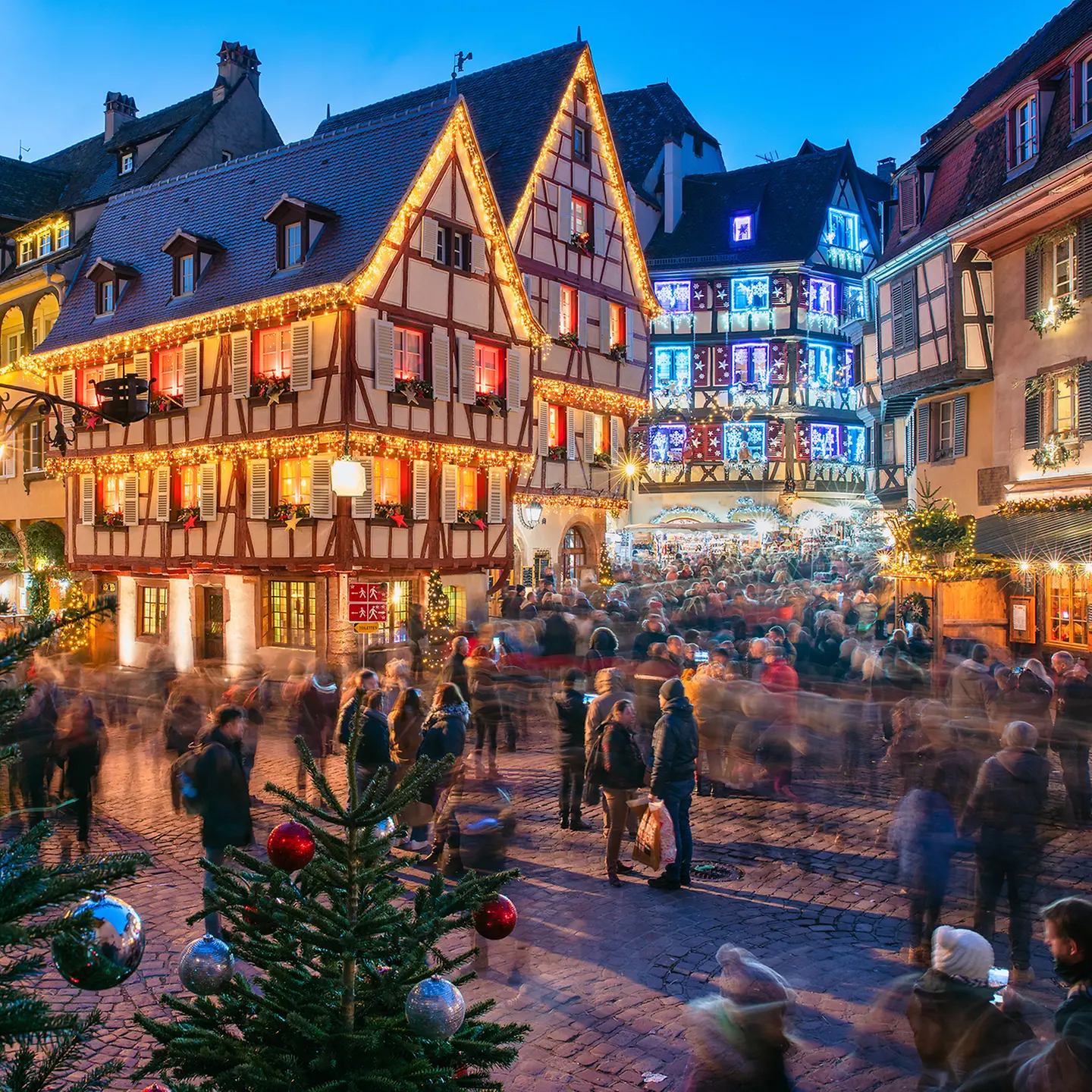 Auf dem Bild zu sehen ist eine weihnachtlich dekorierte Altstadt, wie sie dem weihnachtlichen Klischee entspricht. Es ist bunt, man sieht Tannen, Weihnachtsbaumkugeln.