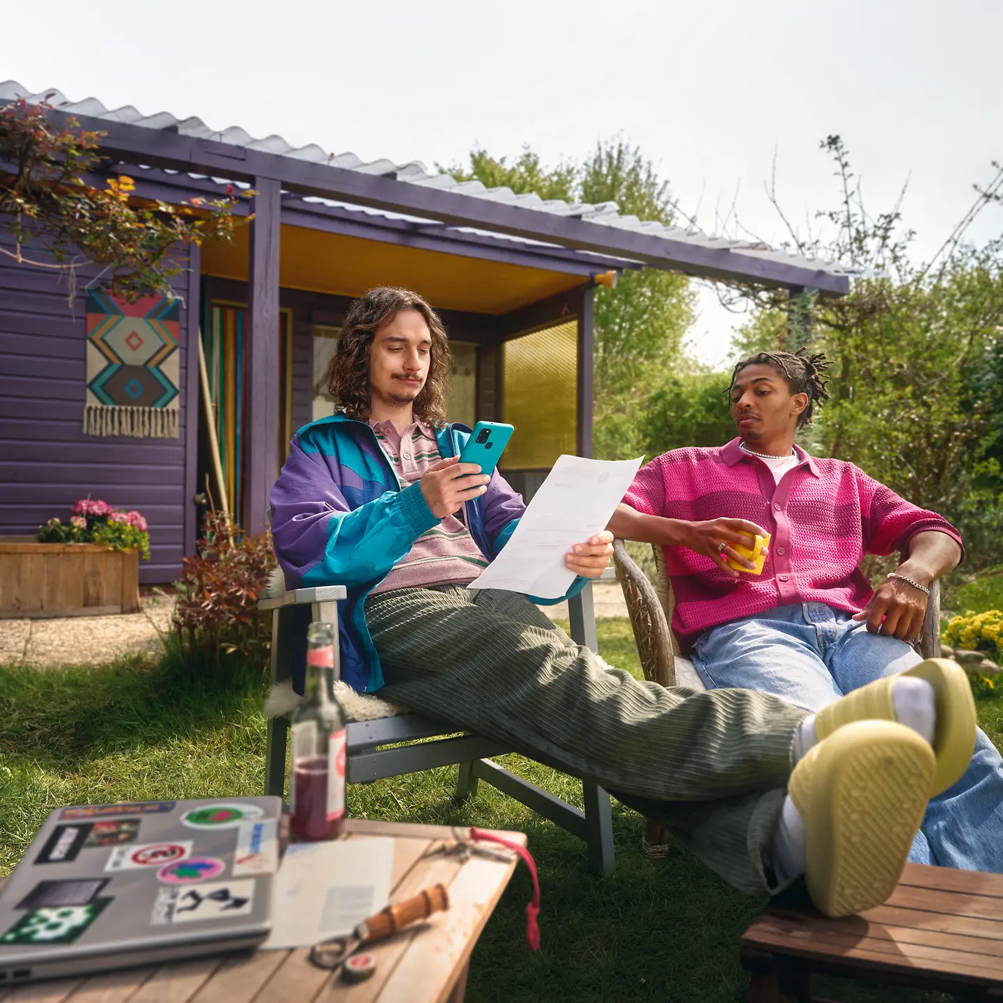 Zwei junge Männer sitzen vor einer Gartenlaube