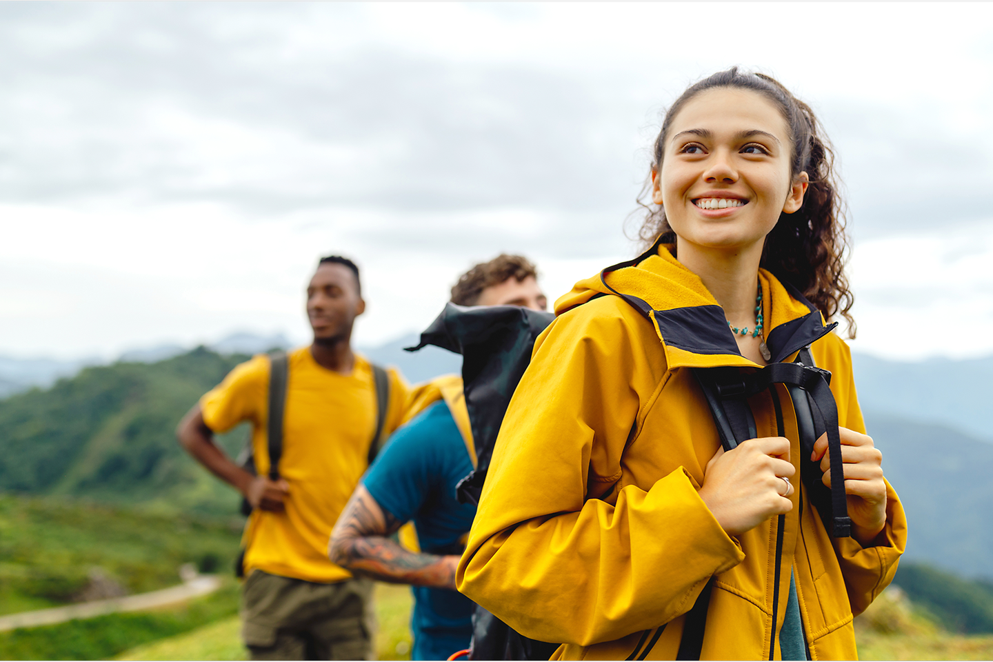 eine Gruppe junger Menschen in gelben Regenjacken wandert durch Landschaft