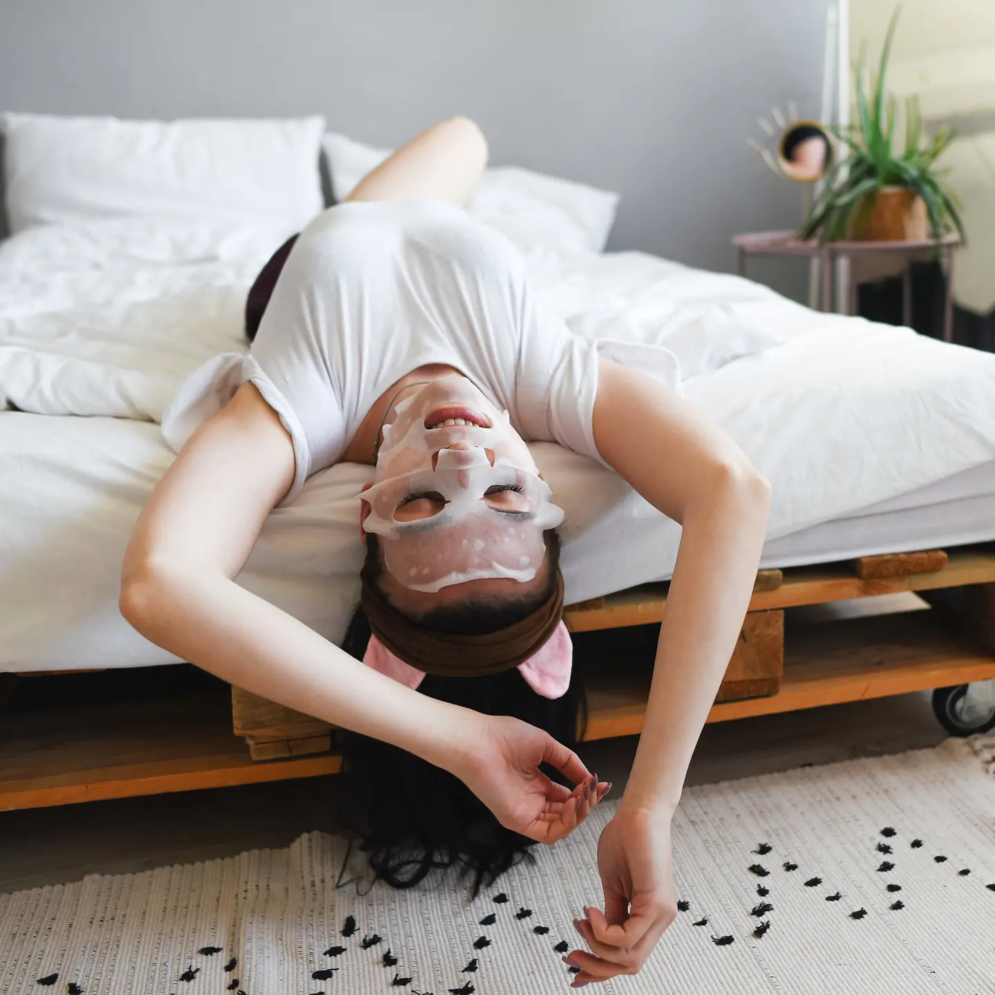 Eine Frau im Schlafanzug liegt im Bett und trägt eine Sheet Mask