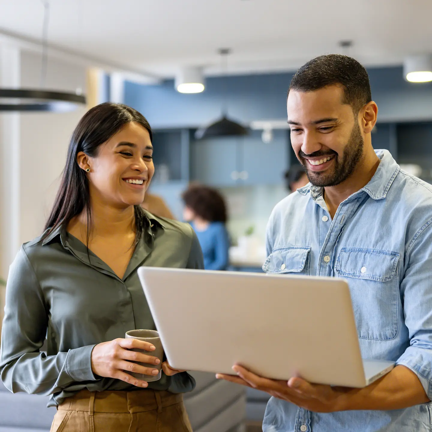 Kollegin und Kollege stehen zusammen mit einem Notebook in den Händen in einer Büro-Küche