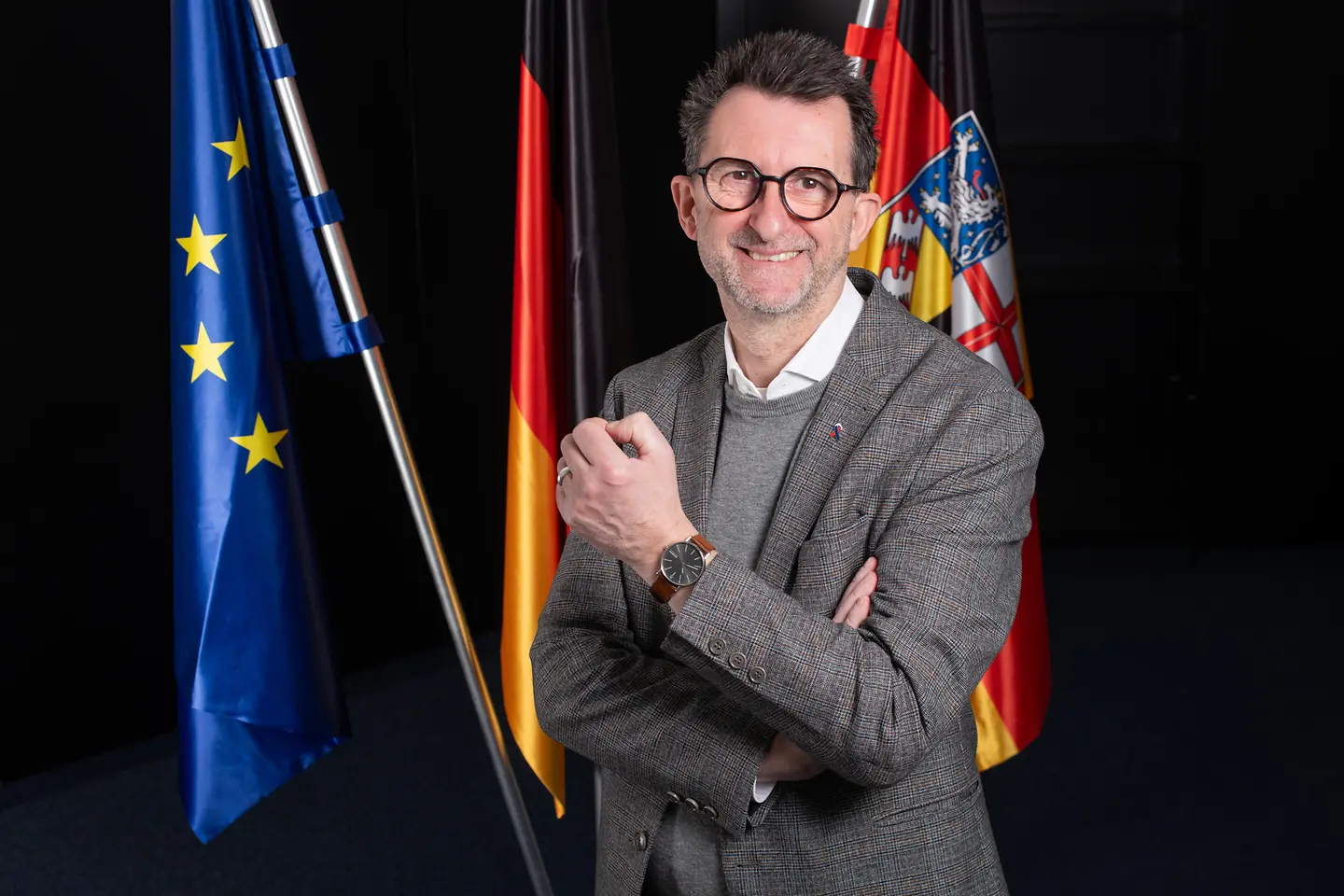 Reinhold Jost steht vor Fahnen.