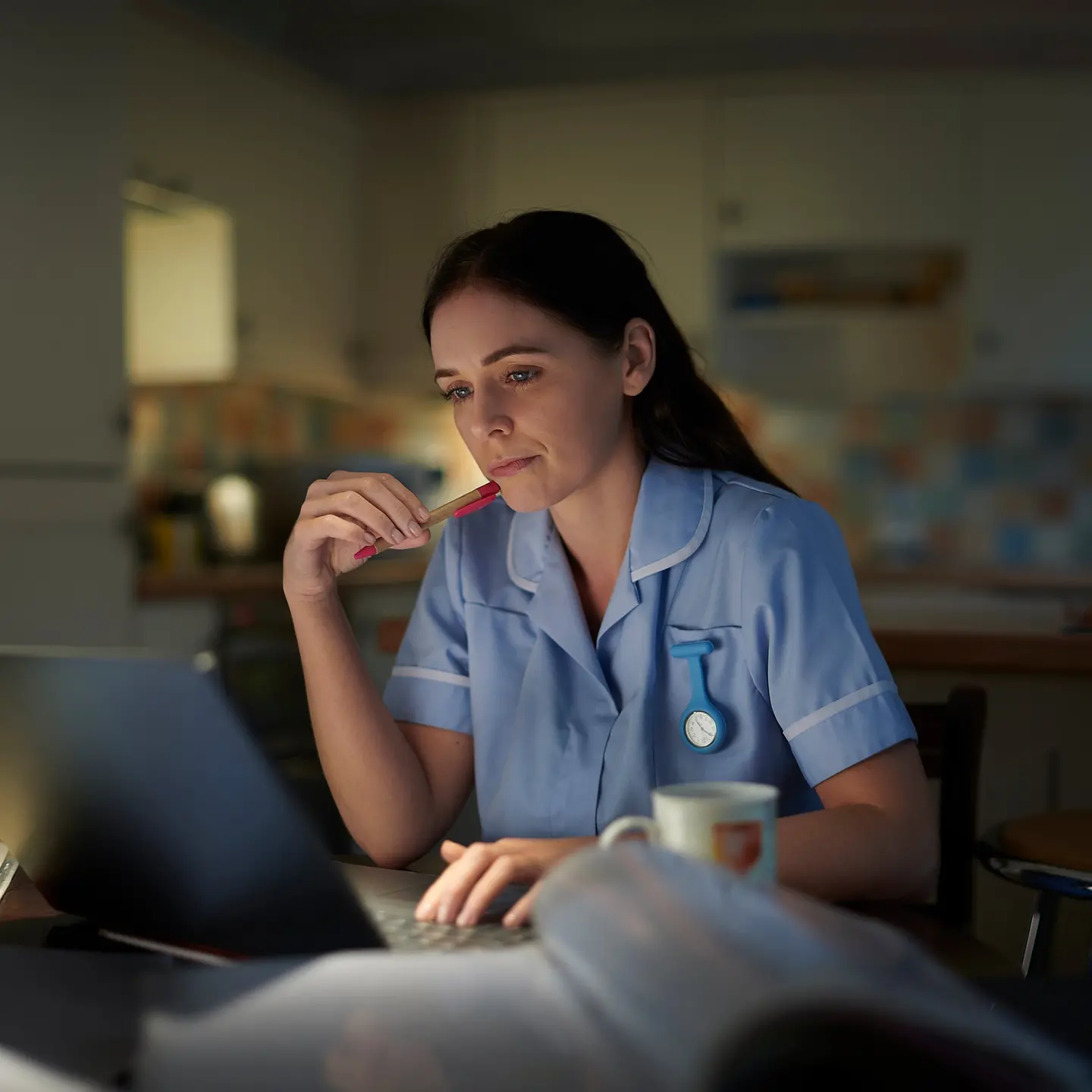 Eine junge Krankenschwester sitzt in der Nacht am Rechner.