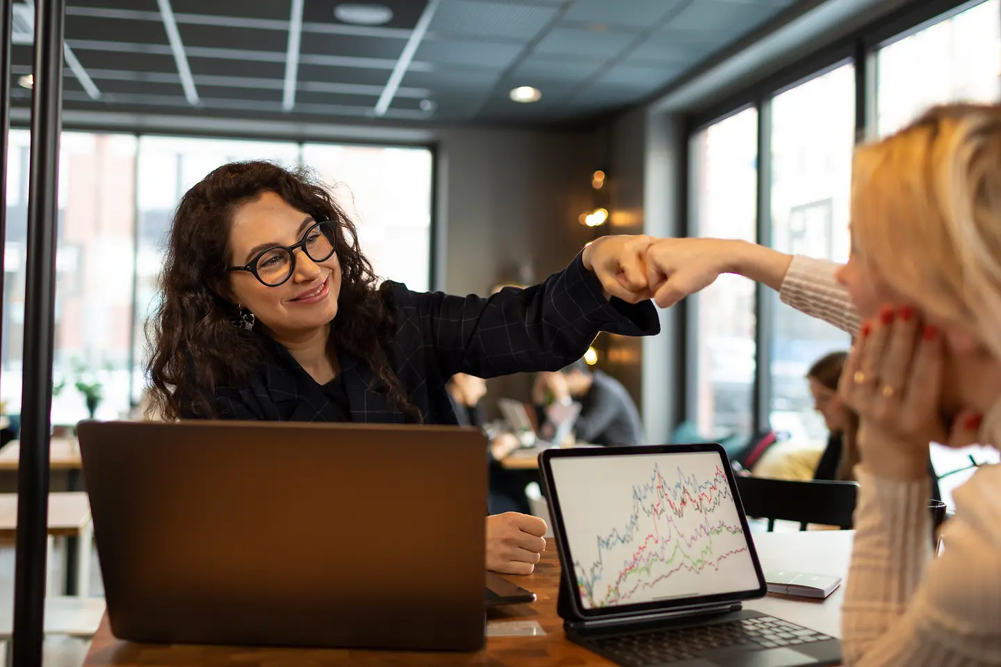 Zwei Frauen im Büro begrüßen sich mit Fäusten
