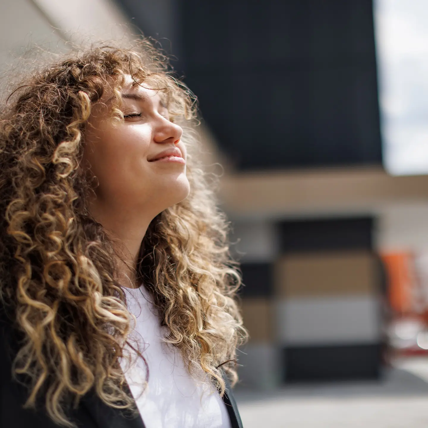 Junge Frau mit Locken entspannt mit geschlossenen Augen