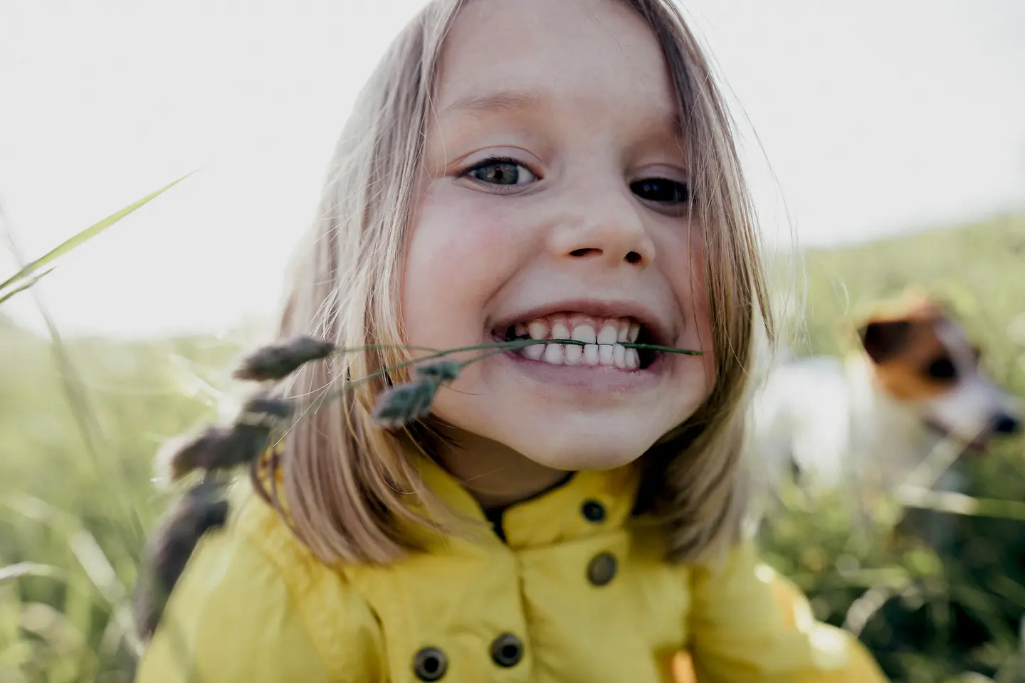 Mädchen mit Grashalm zwischen den Zähne