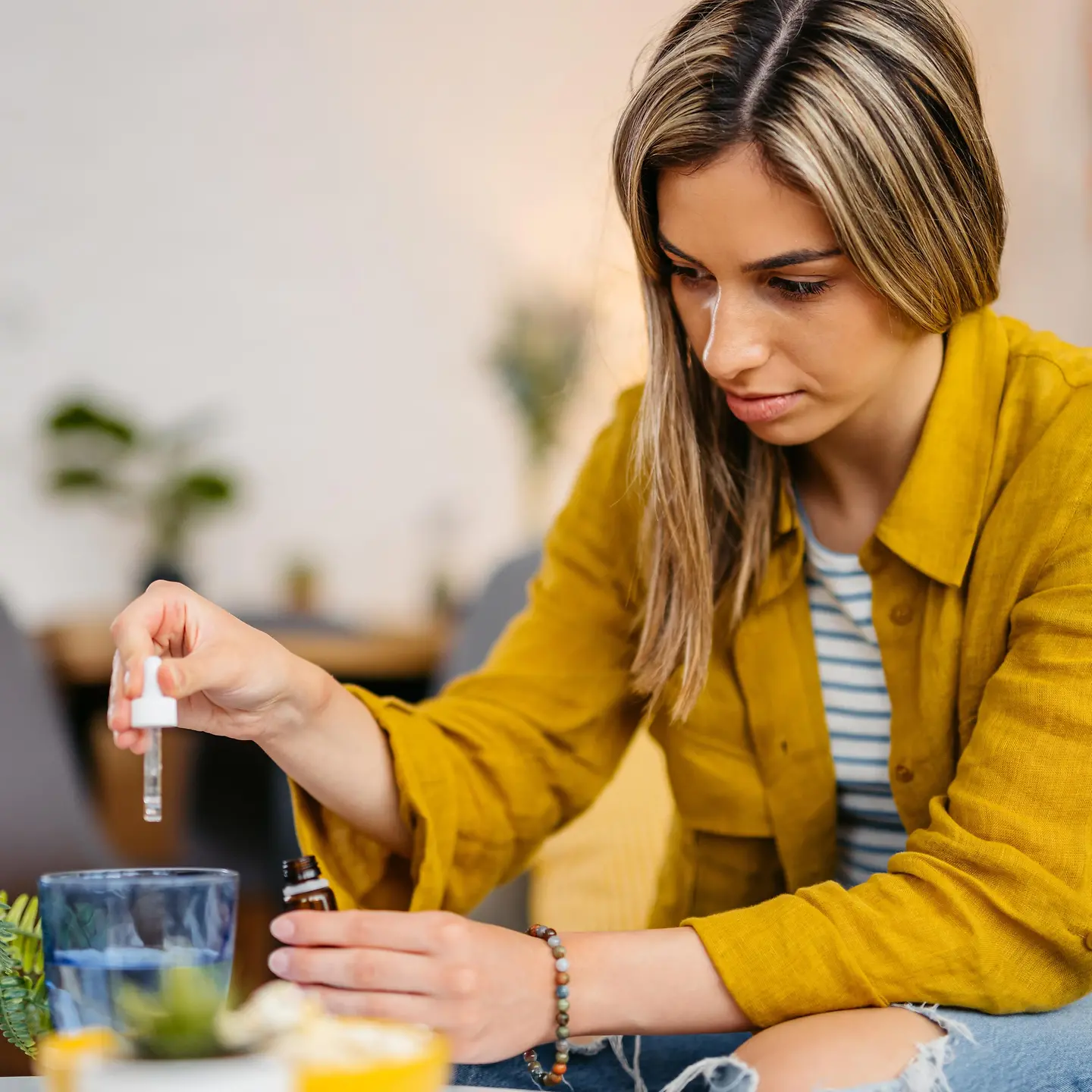 Junge Frau tropft Medizin in ein Wasserglas