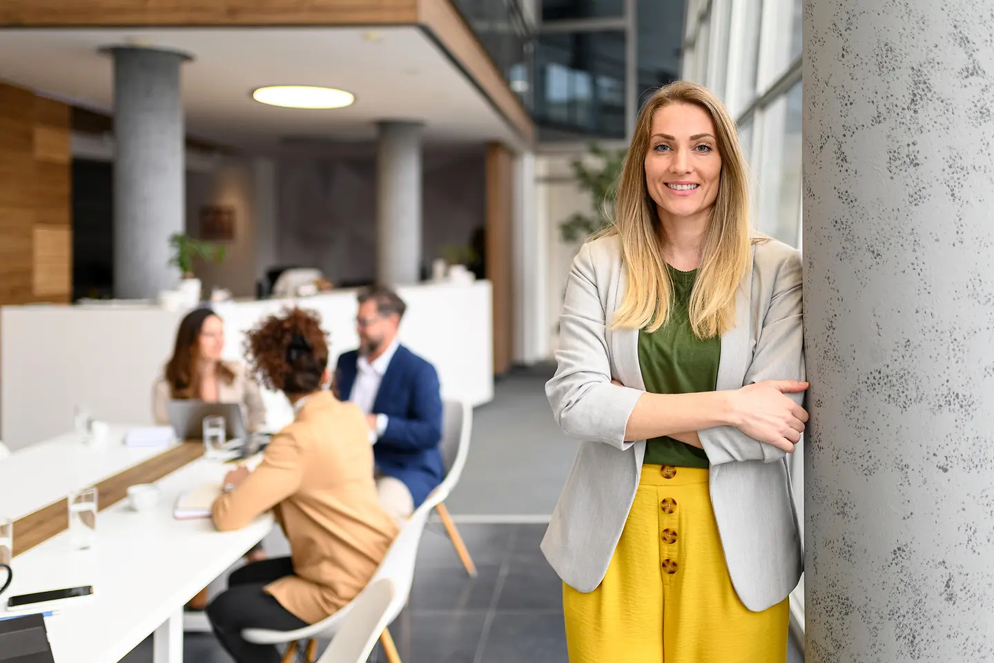 Aufnahme einer sehr nett lächelnden Geschäftsfrau, die in einem Büro steht und ein Team betreut