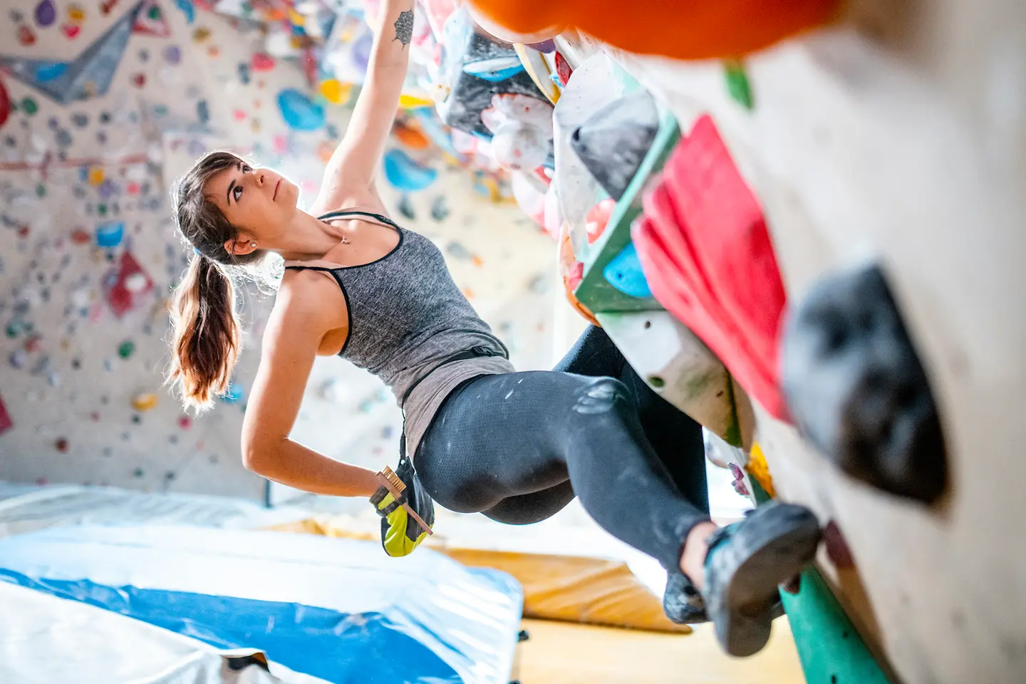 Eine junge Frau beim Bouldern greift nach Chalk