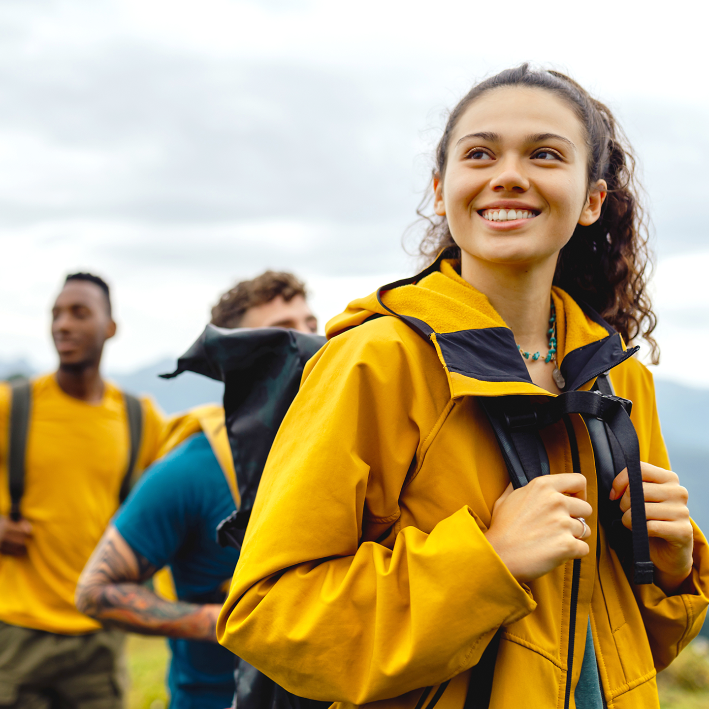 eine Gruppe junger Menschen in gelben Regenjacken wandert durch Landschaft