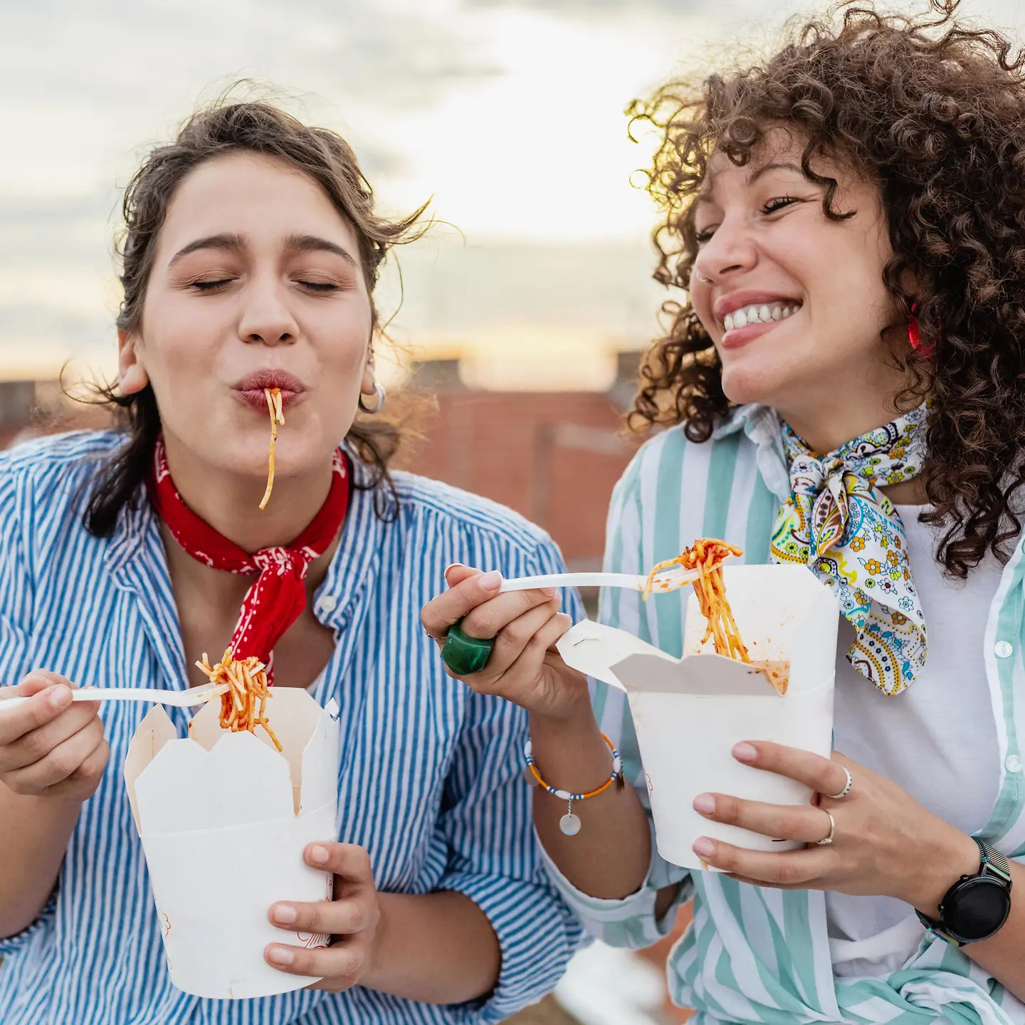 Zwei Frauen essen draußen Streetfood
