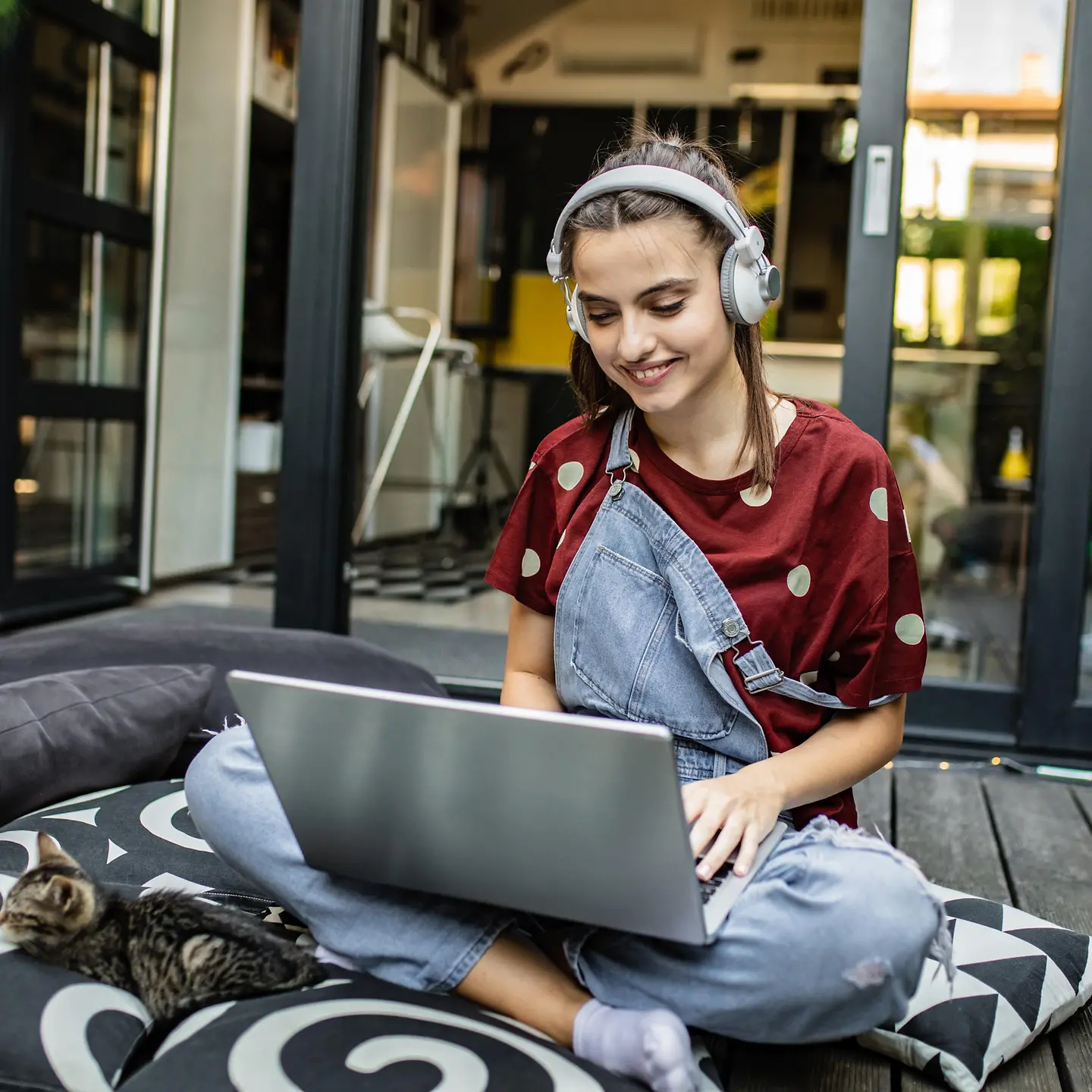 Eine junge Frau mit Kopfhörer arbeitet zuhause an ihrem Laptop