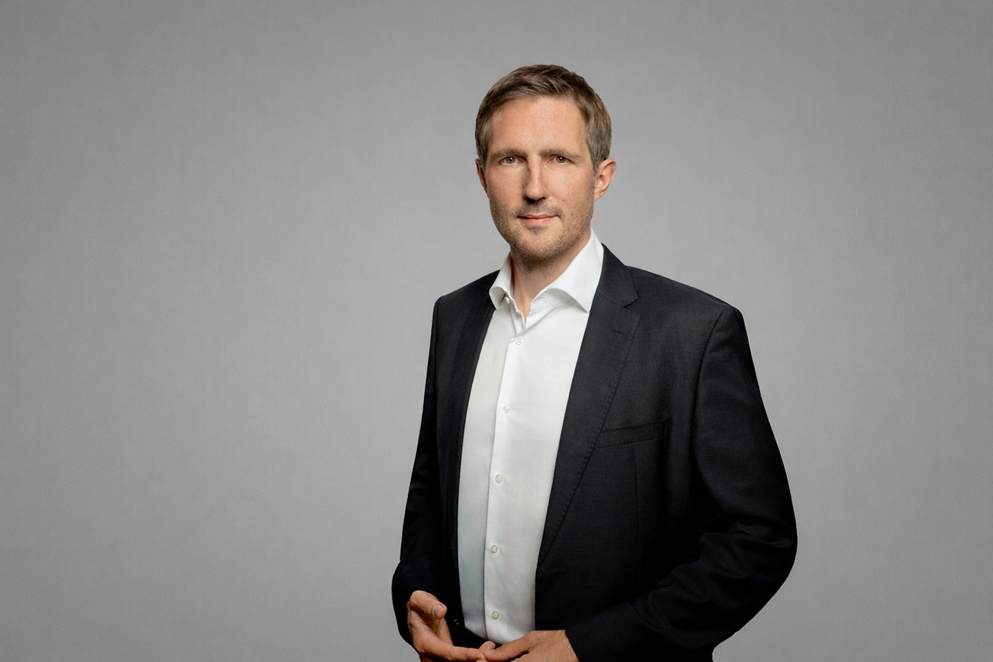 Christoph Gensch steht vor einer grauen Wand.