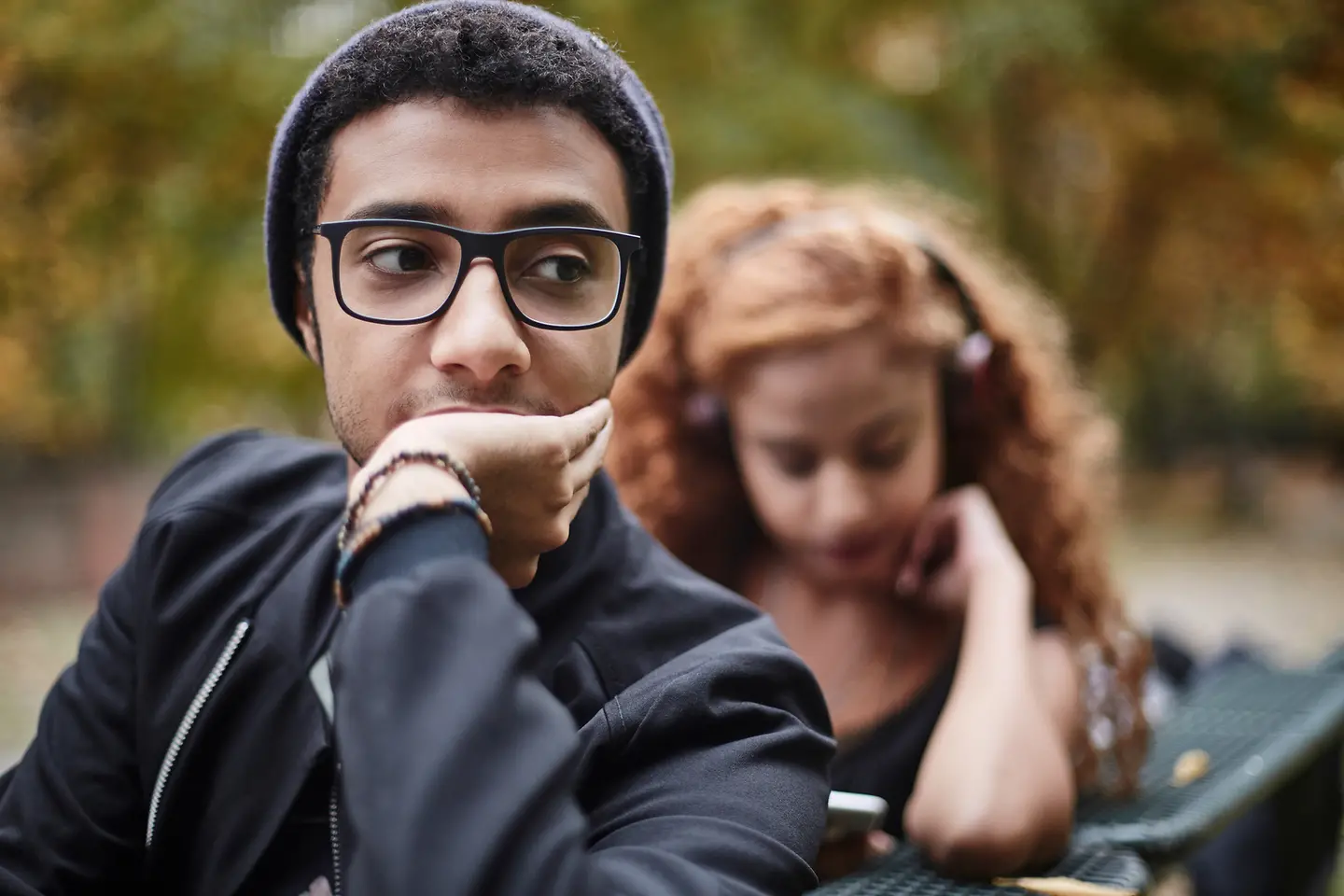 Ein junges Paar sitzt auf einer Bank und schaut nachdenklich.