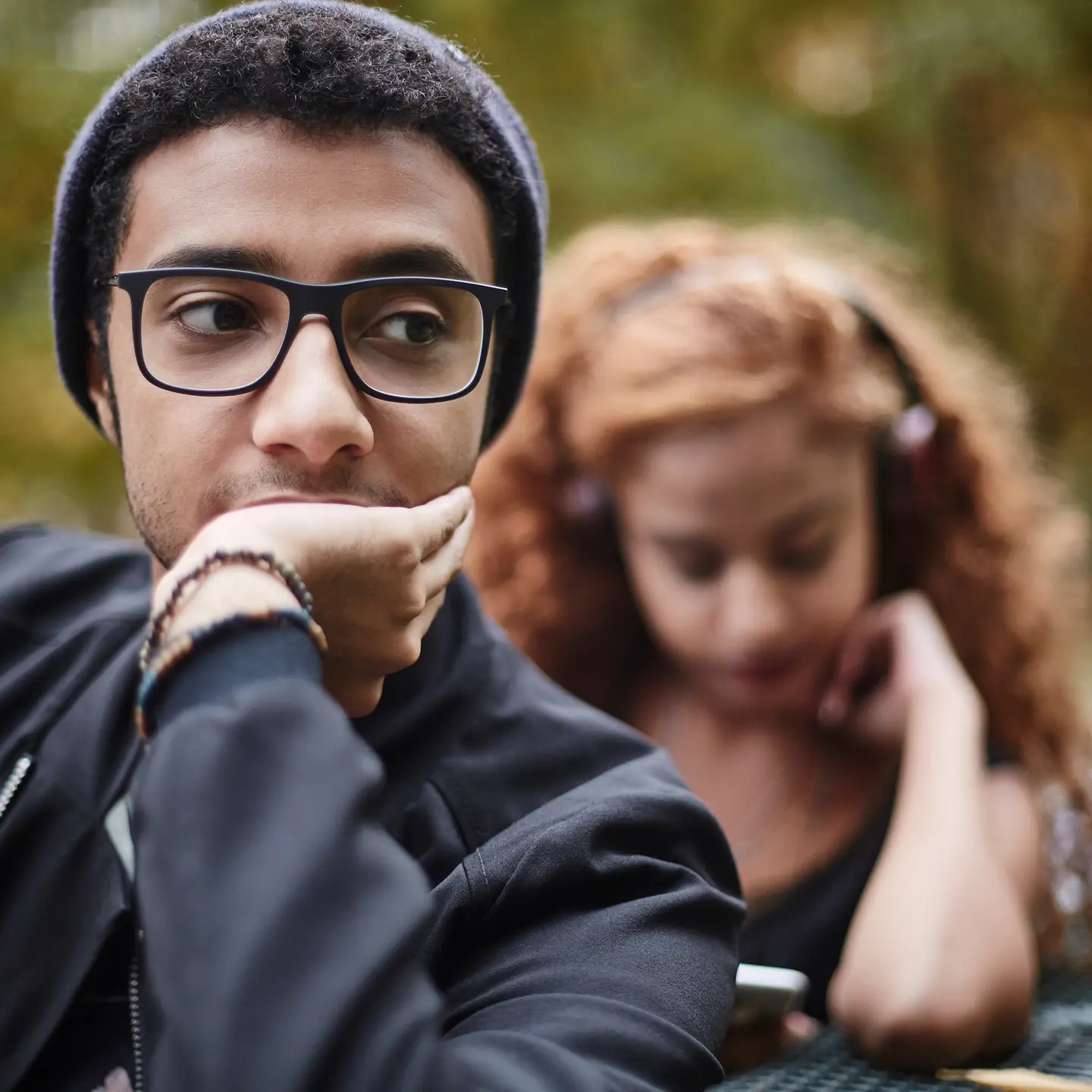 Ein junges Paar sitzt auf einer Bank und schaut nachdenklich.