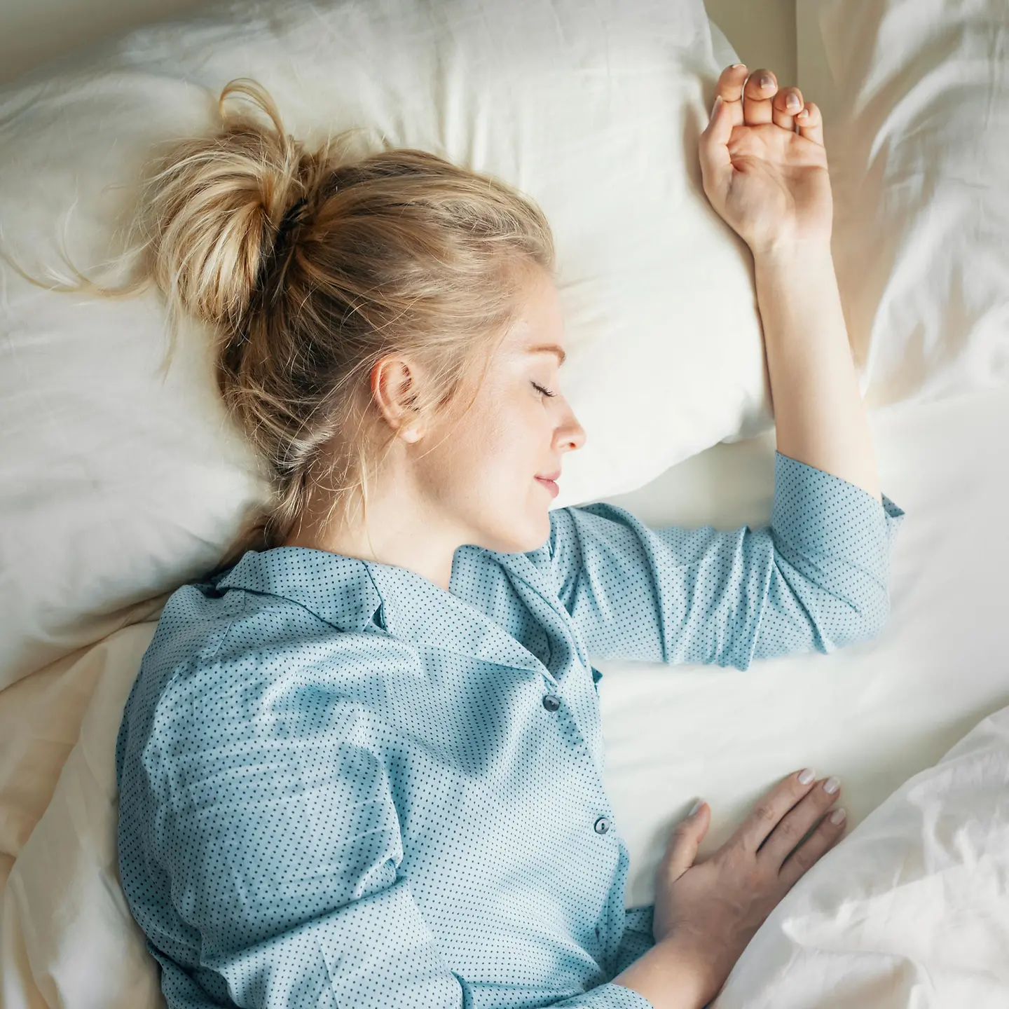 Junge Frau im hellblauem Pyjama, schlafend im Bett