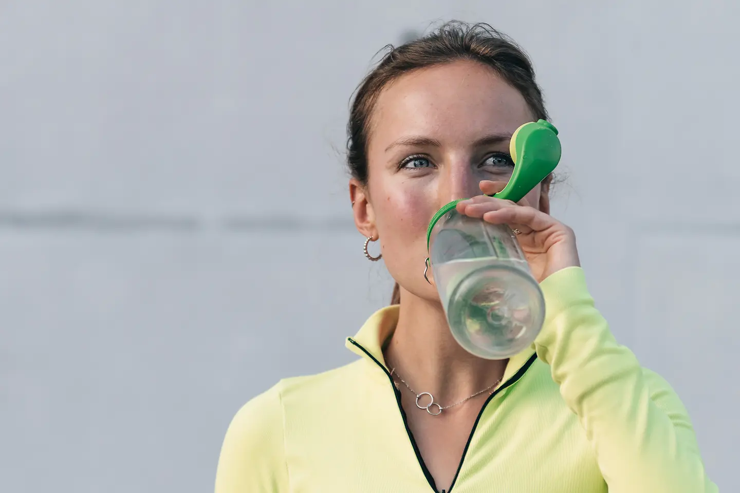 Porträt einer Frau, die nach dem Sport aus einer Plastikflasche trinkt