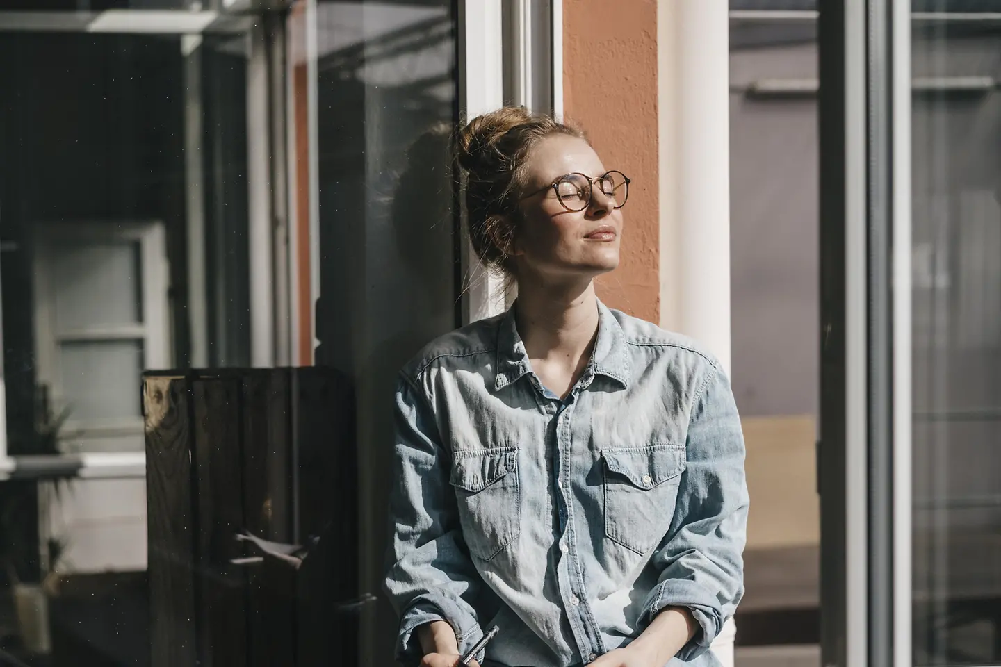 Eine Frau sitzt mit geschlossenen Augen in der Sonne. 
