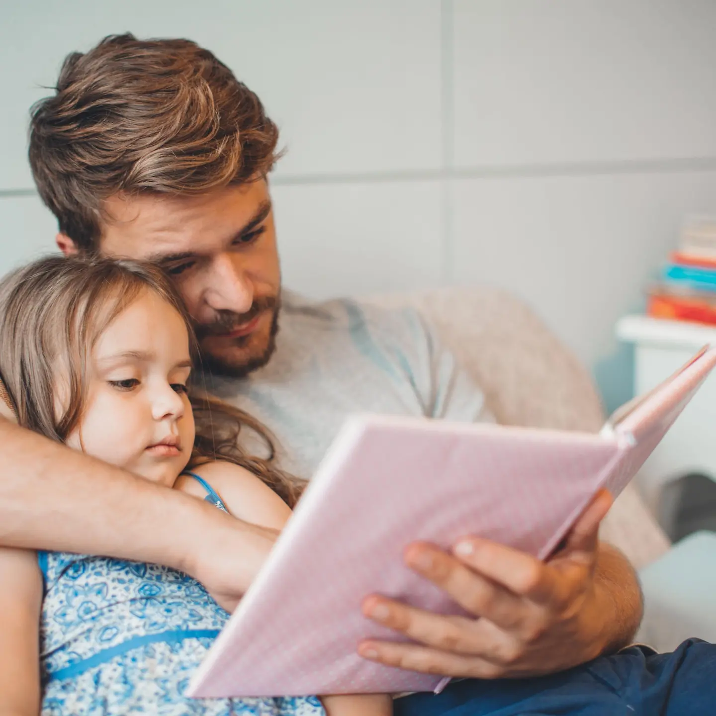 Ein Vater schaut sich mit seiner Tochter ein Bilderbuch an.