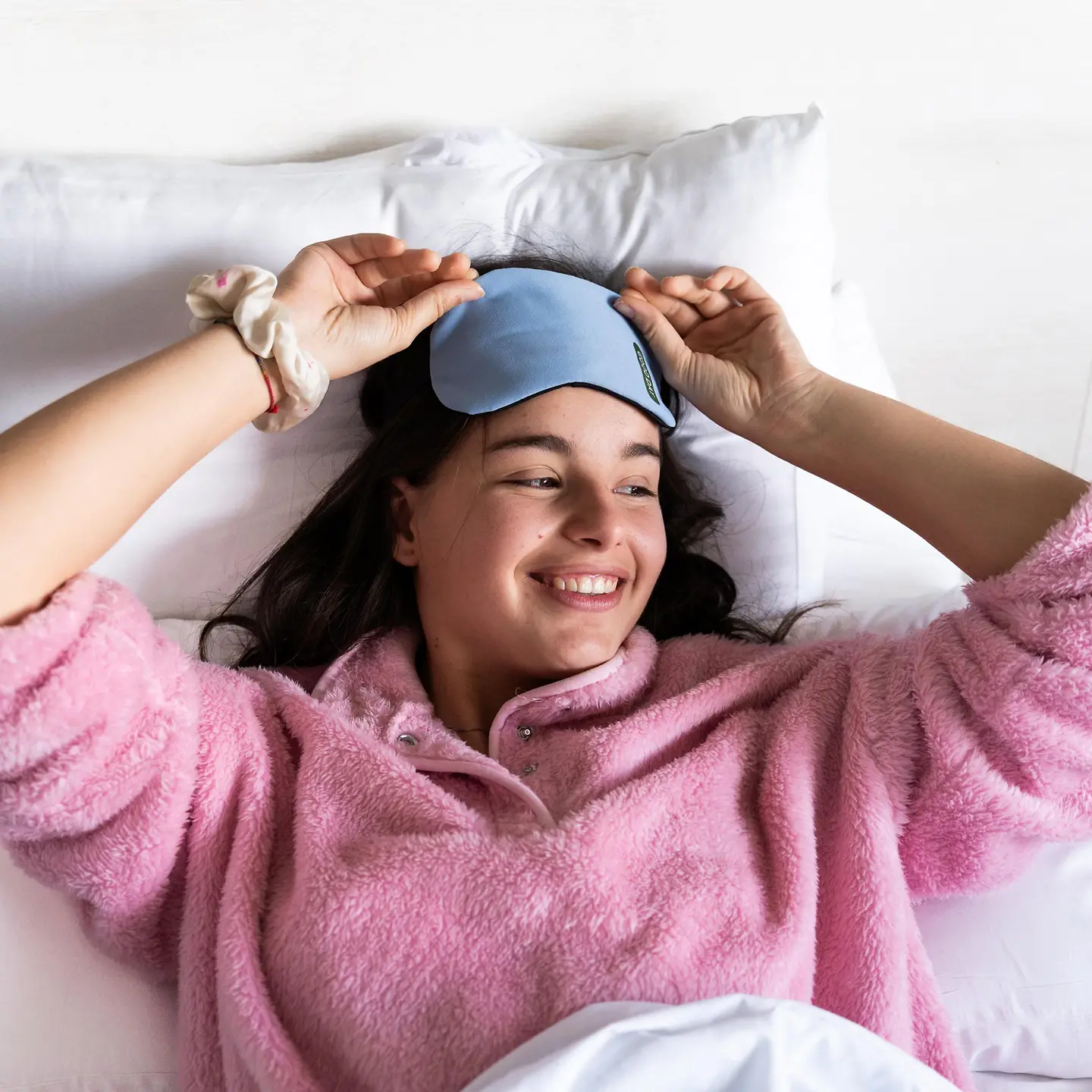 Eine junge Frau wacht auf und nimmt ihre Schlafmaske ab