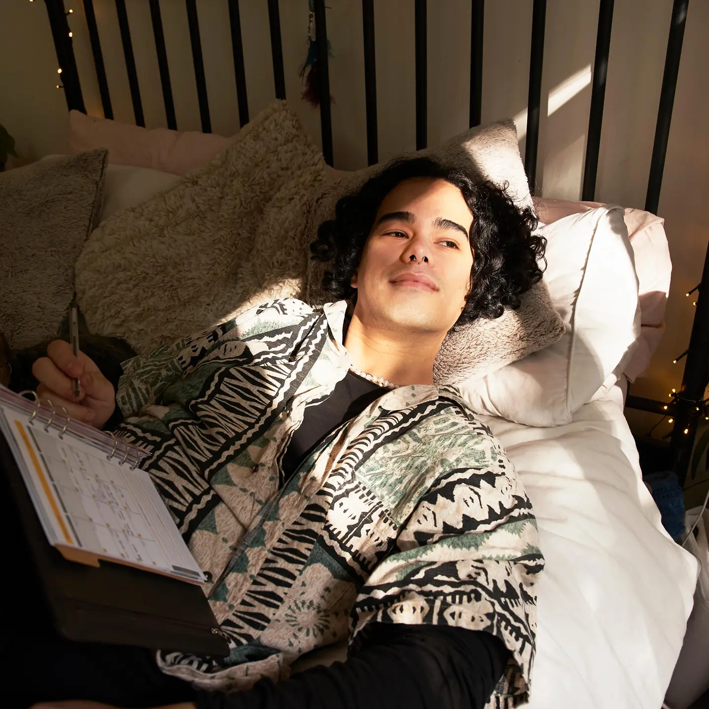 Junger Mann schreibt in seinen Kalender und schaut ins Sonnenlicht