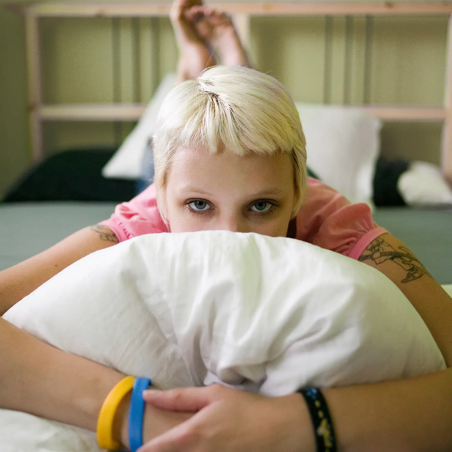 Eine Frau liegt auf dem Bett und hat ein Kissen vor dem Gesicht