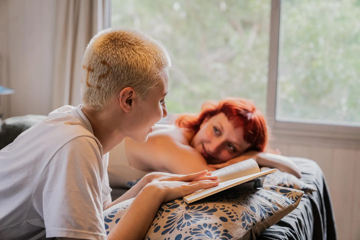 Freundinnen liegen auf einem Bett und lesen ein Buch