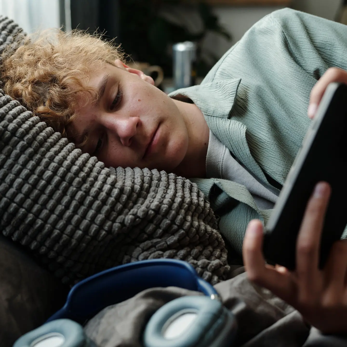 Jugendlicher liegt im Bett und schaut auf sein Handy