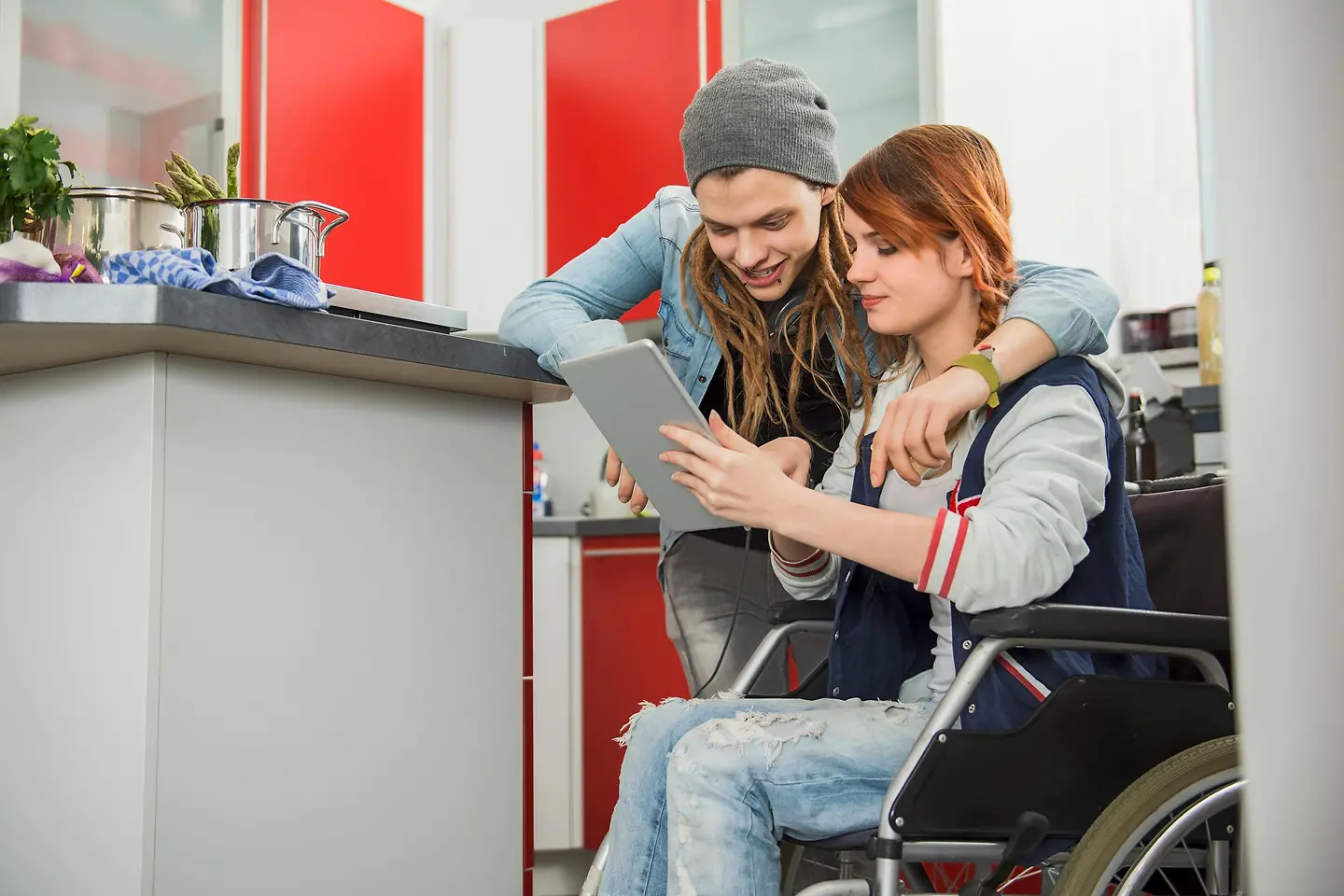 Junges Mädchen im Rollstuhl und ein junger Mann sind gemeinsam in der Küche