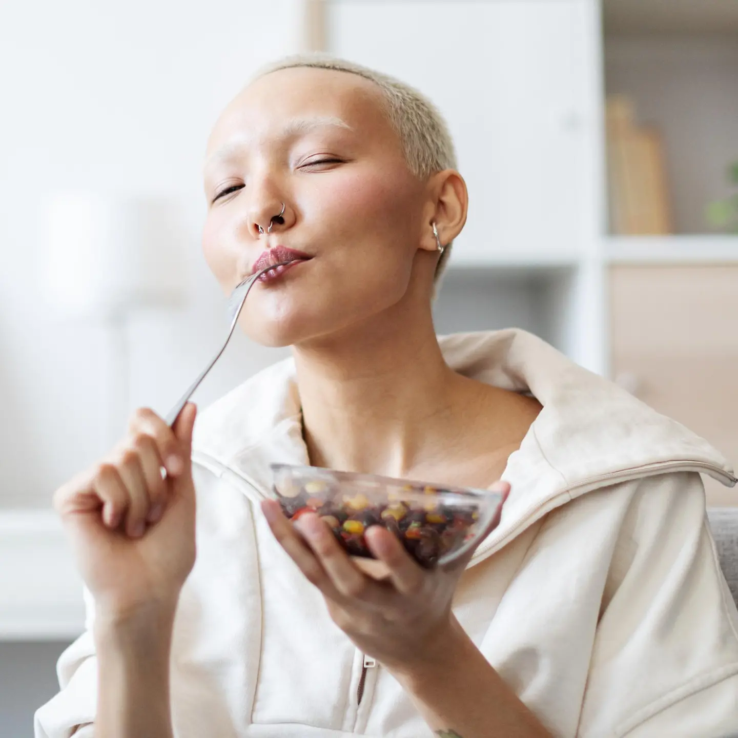 Eine junge Frau isst einen Bohnensalat und sieht entspannt und glücklich aus