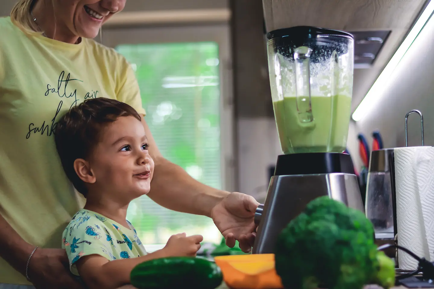 Eine Frau macht mit ihrem Sohn einen grünen Smoothie