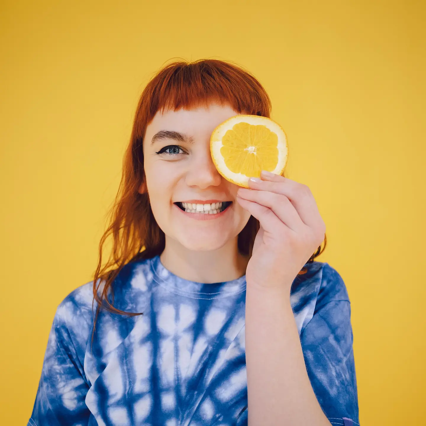 Fröhliche junge Frau mit einer Orange