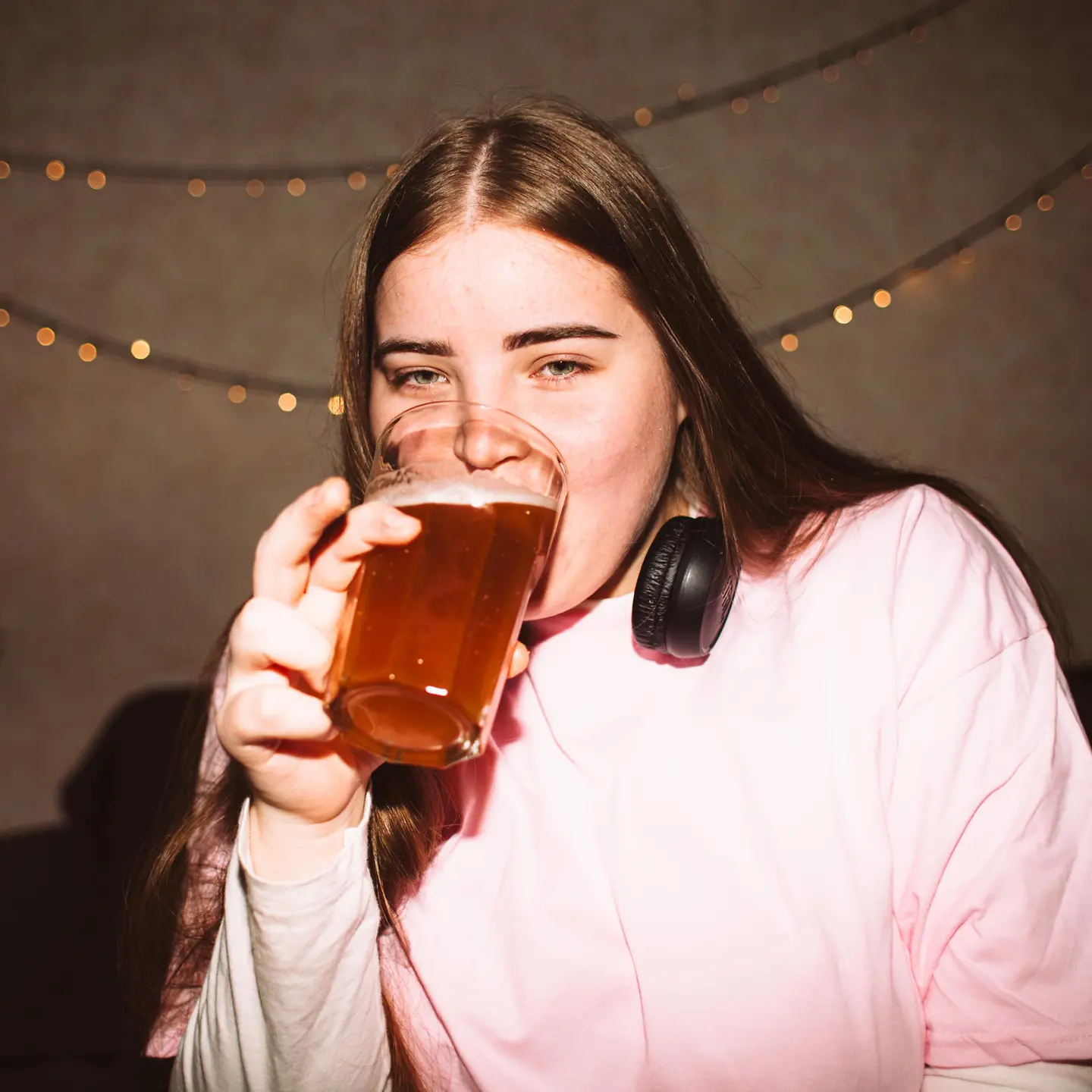 Junge Frau trinkt ein Bier bei einer Party