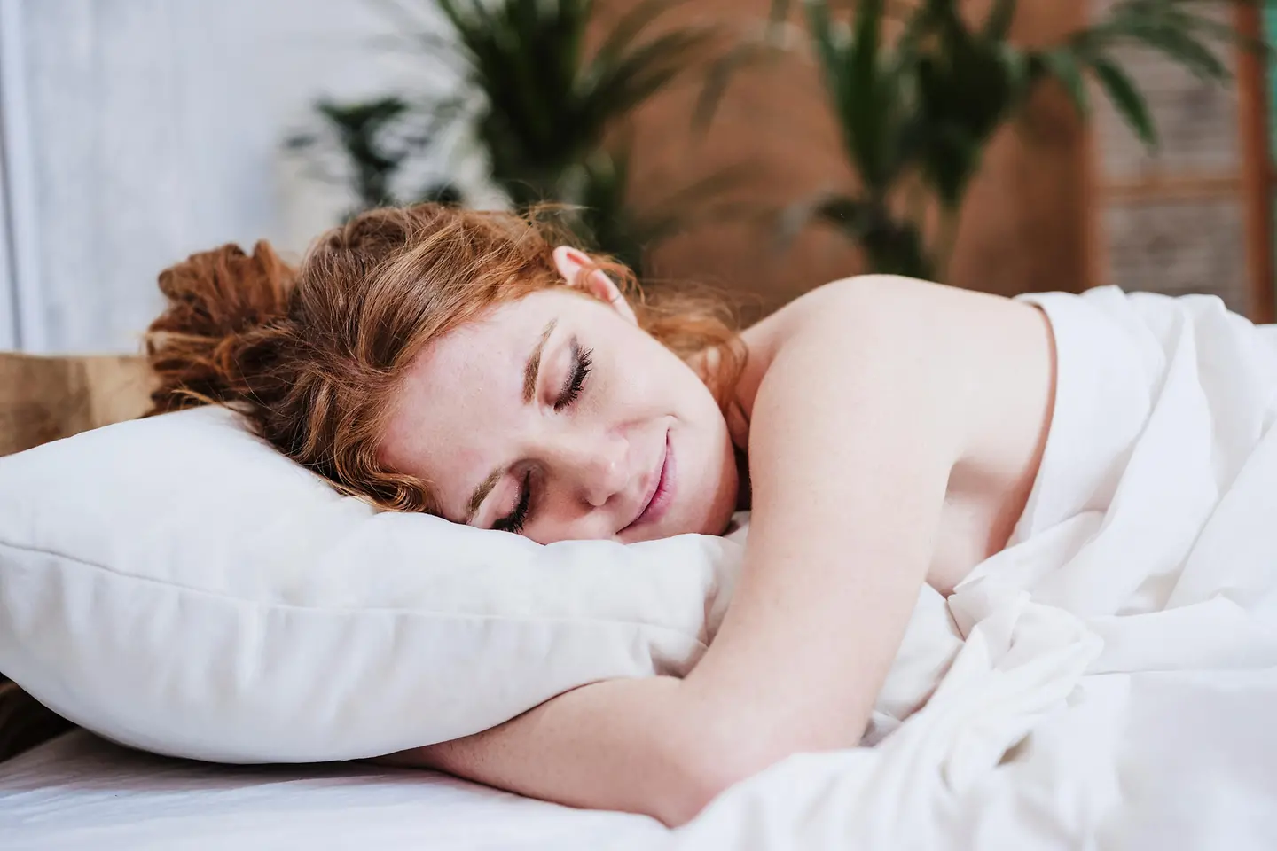 Junge Frau schläft in ihrem Bett mit weißer Bettwäsche